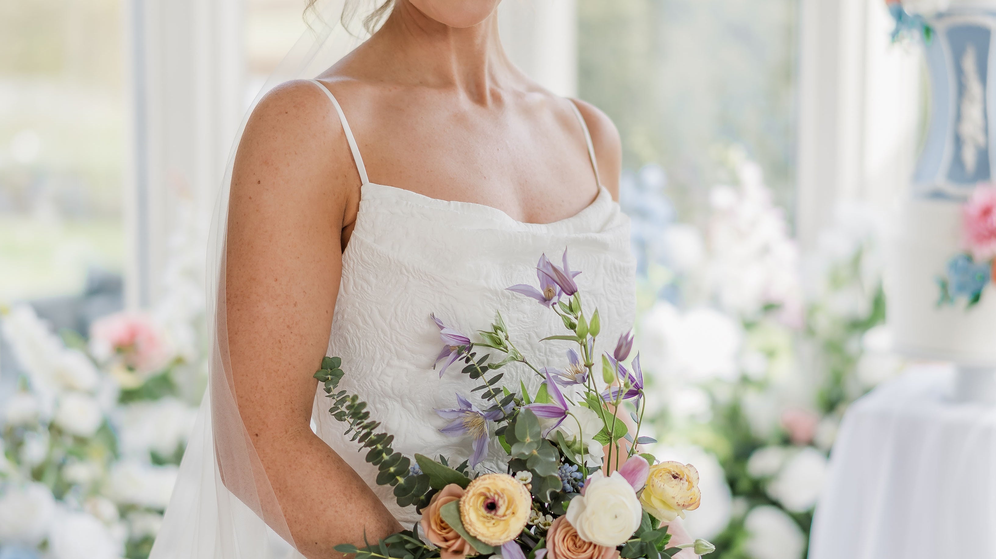 bride with large floral bouquet of pastel coloured flowers, in a large bay window for regency bridgerton style wedding