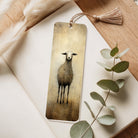 Bookmark with a sheep illustration on a wooden surface with eucalyptus leaves