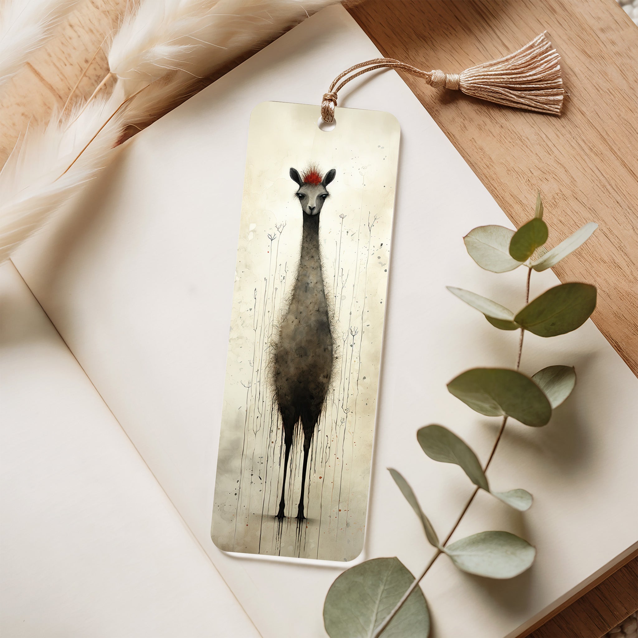 Bookmark with a llama design on a wooden surface with eucalyptus leaves