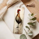 Decorative bookmark with a cockerel design on a wooden surface with eucalyptus leaves.