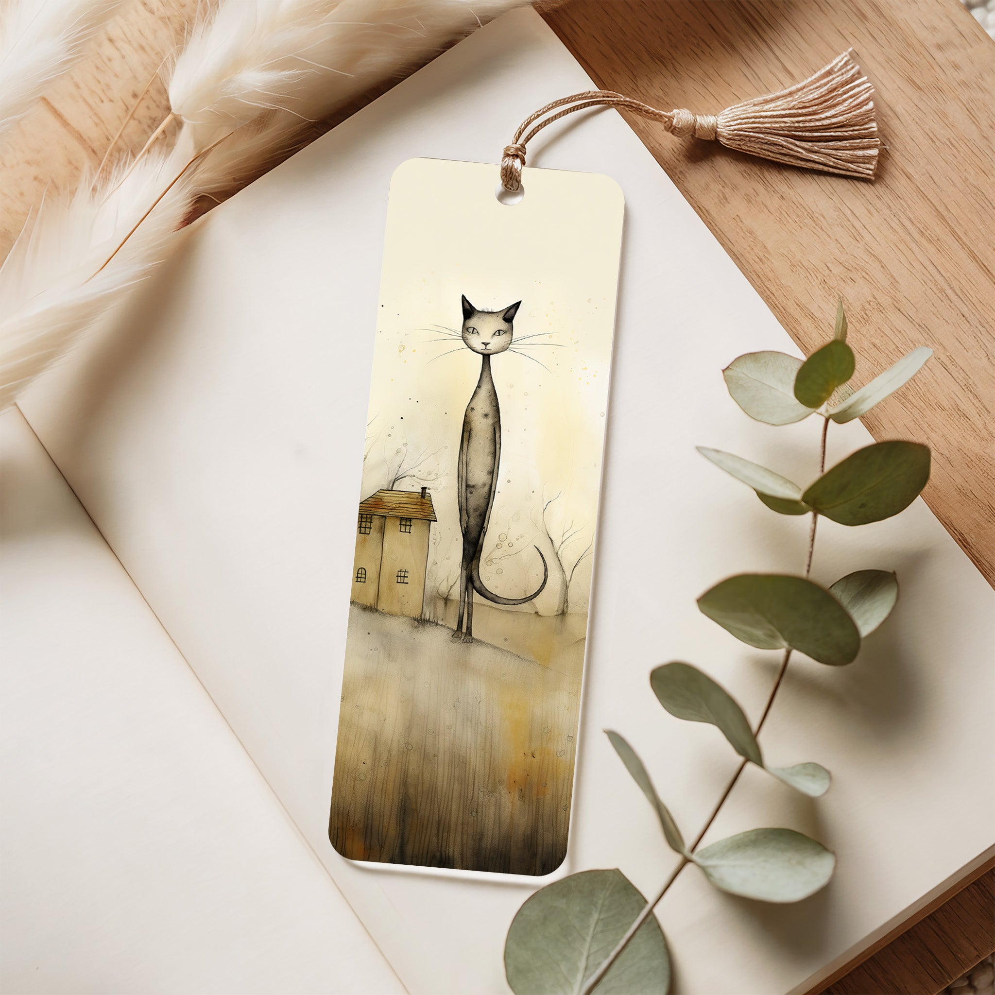 Bookmark with a cat illustration on a wooden surface with eucalyptus leaves