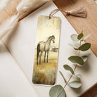 Bookmark with horse illustration on a wooden surface with eucalyptus leaves