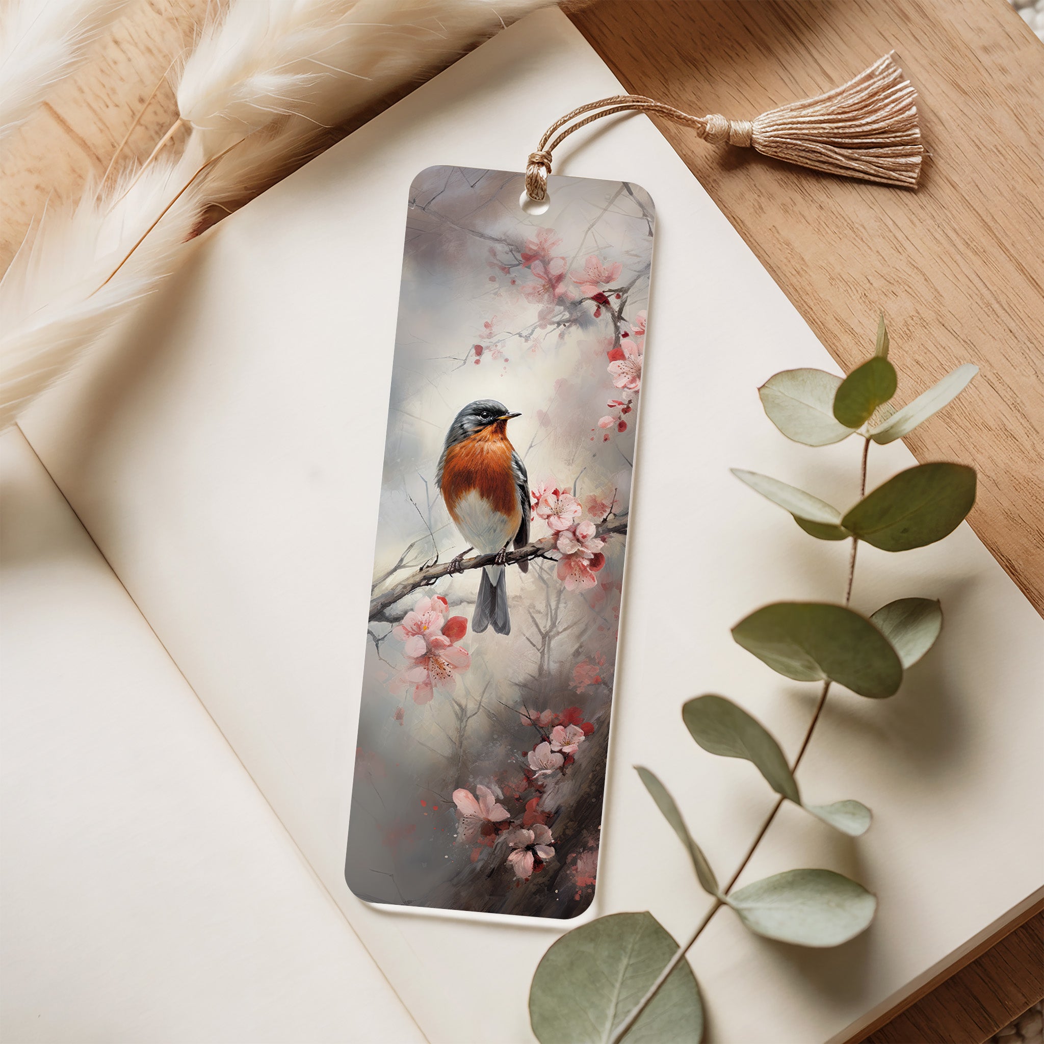 Decorative bookmark with a bird and floral design on a wooden surface with eucalyptus leaves.