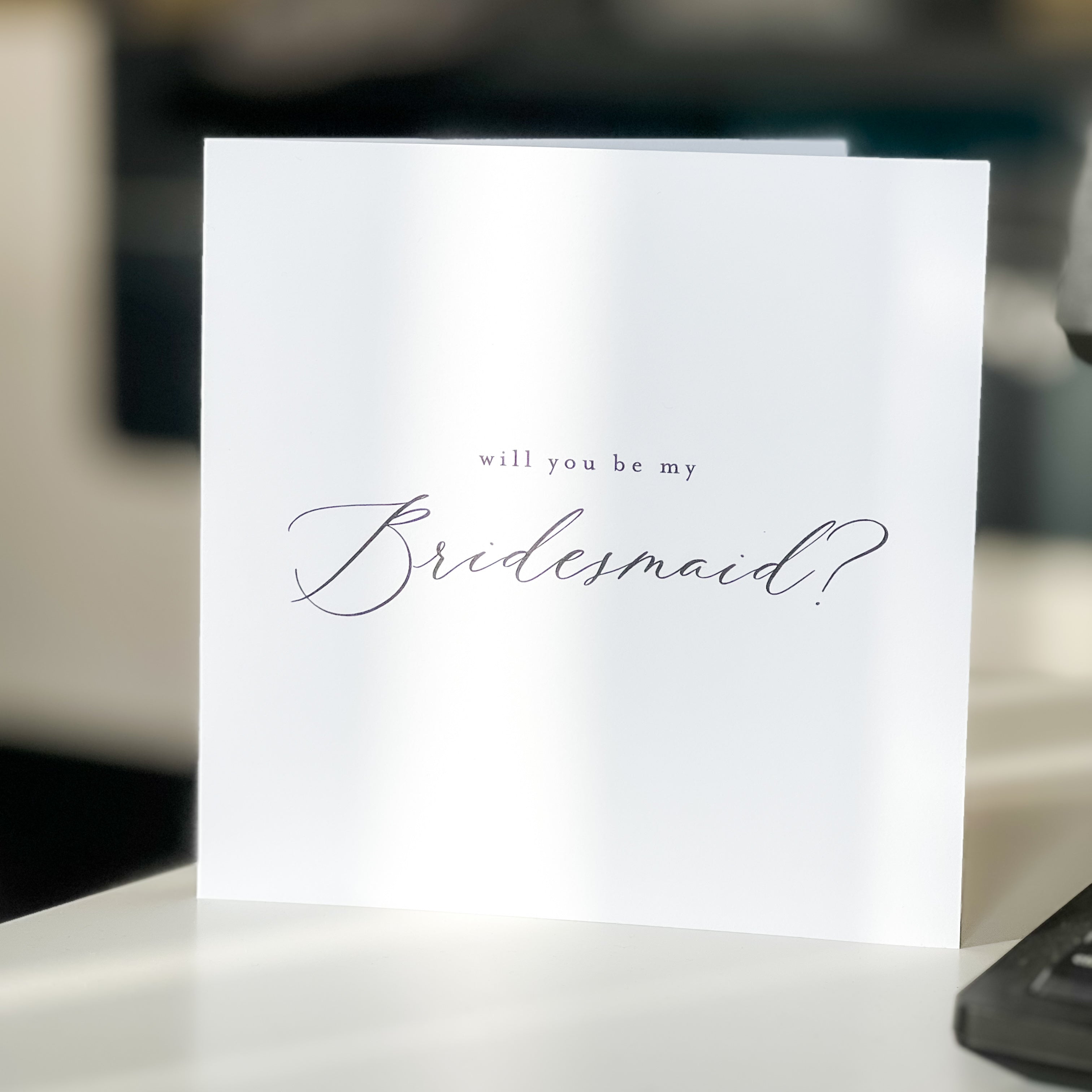 Greeting card asking 'will you be my Bridesmaid?' on a blurred background