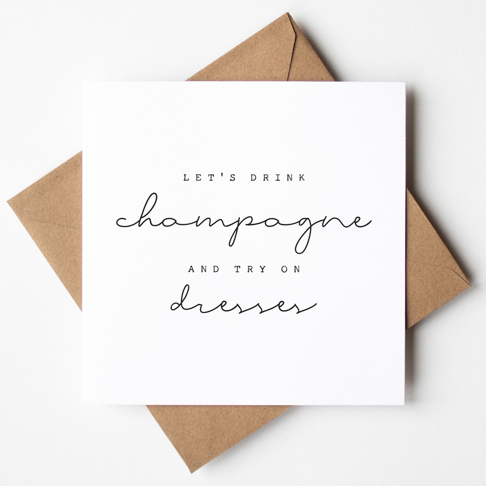 Card with text 'Let's drink champagne and try on dresses' on a white background with brown envelope.