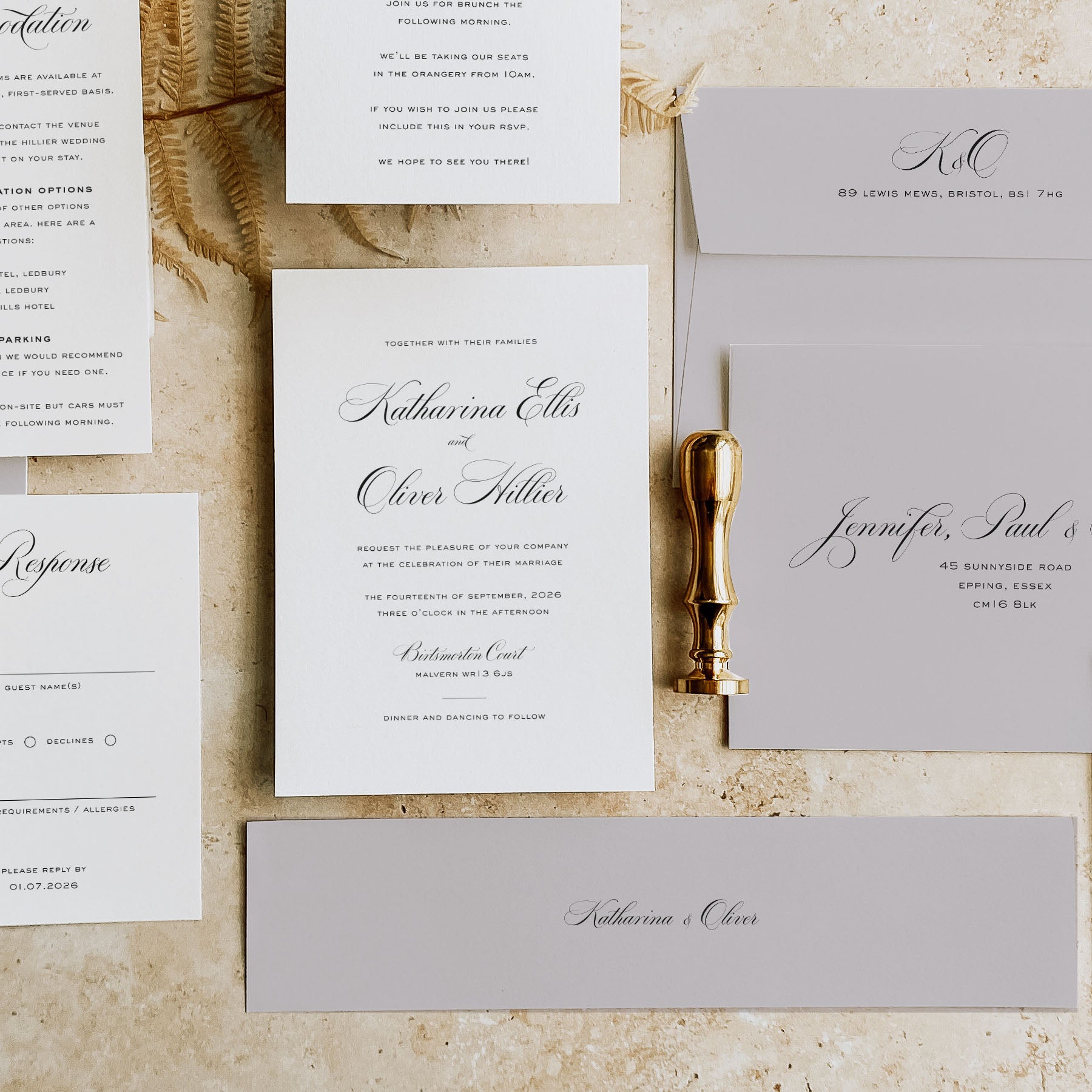 Wedding invitation set with RSVP card, envelope, and gold wax seal on a textured surface.