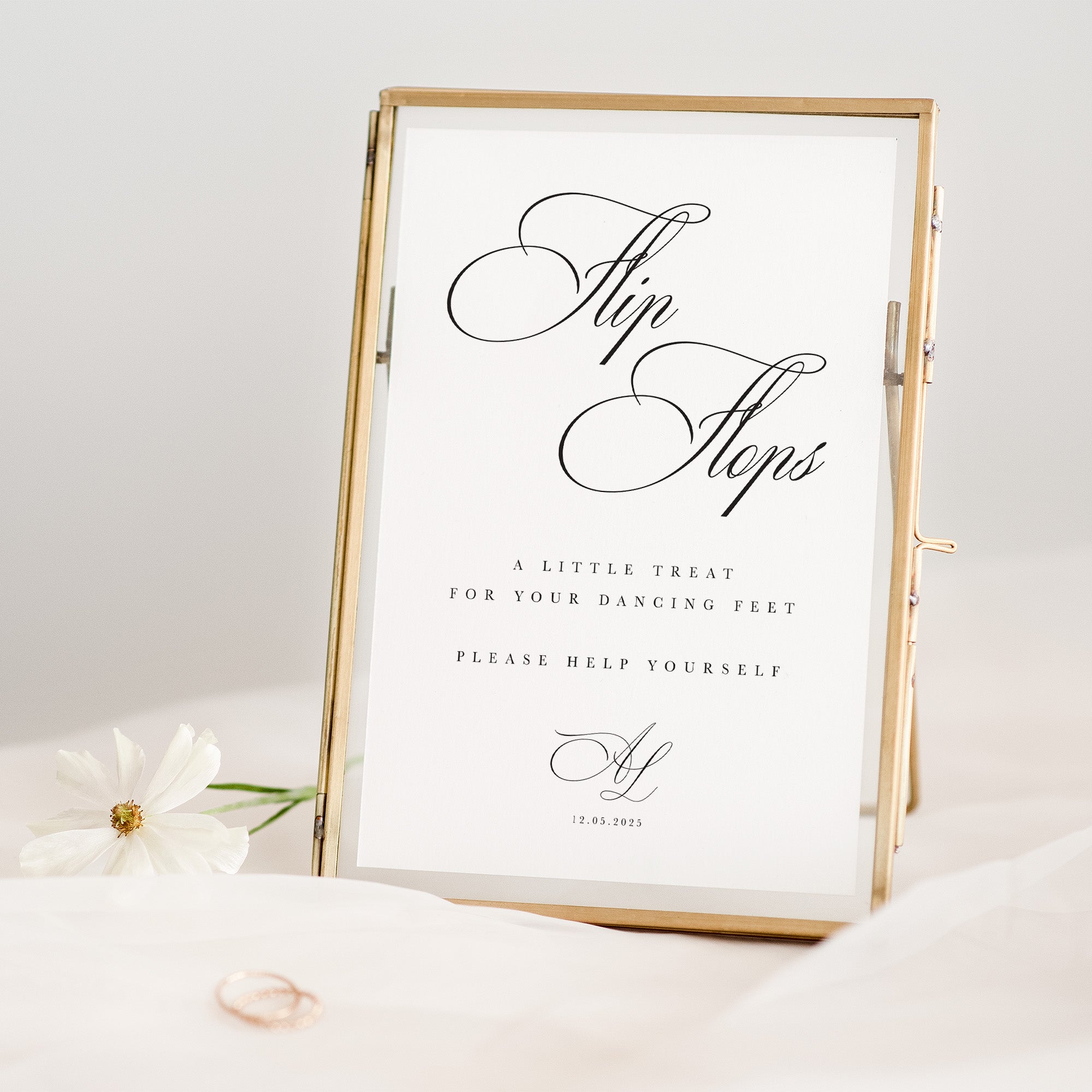 Decorative sign with text in a gold frame on a white surface with flowers.