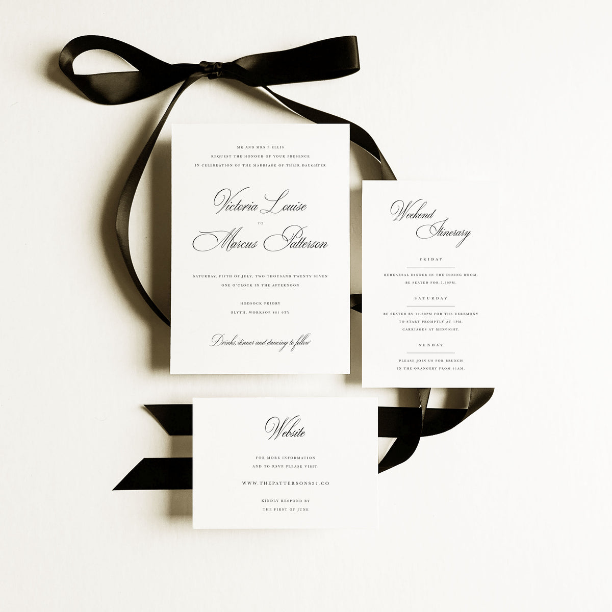 A calligraphy wedding invitation set showing an invitation, weekend itinerary card and website response card on a white background with black ribbon.