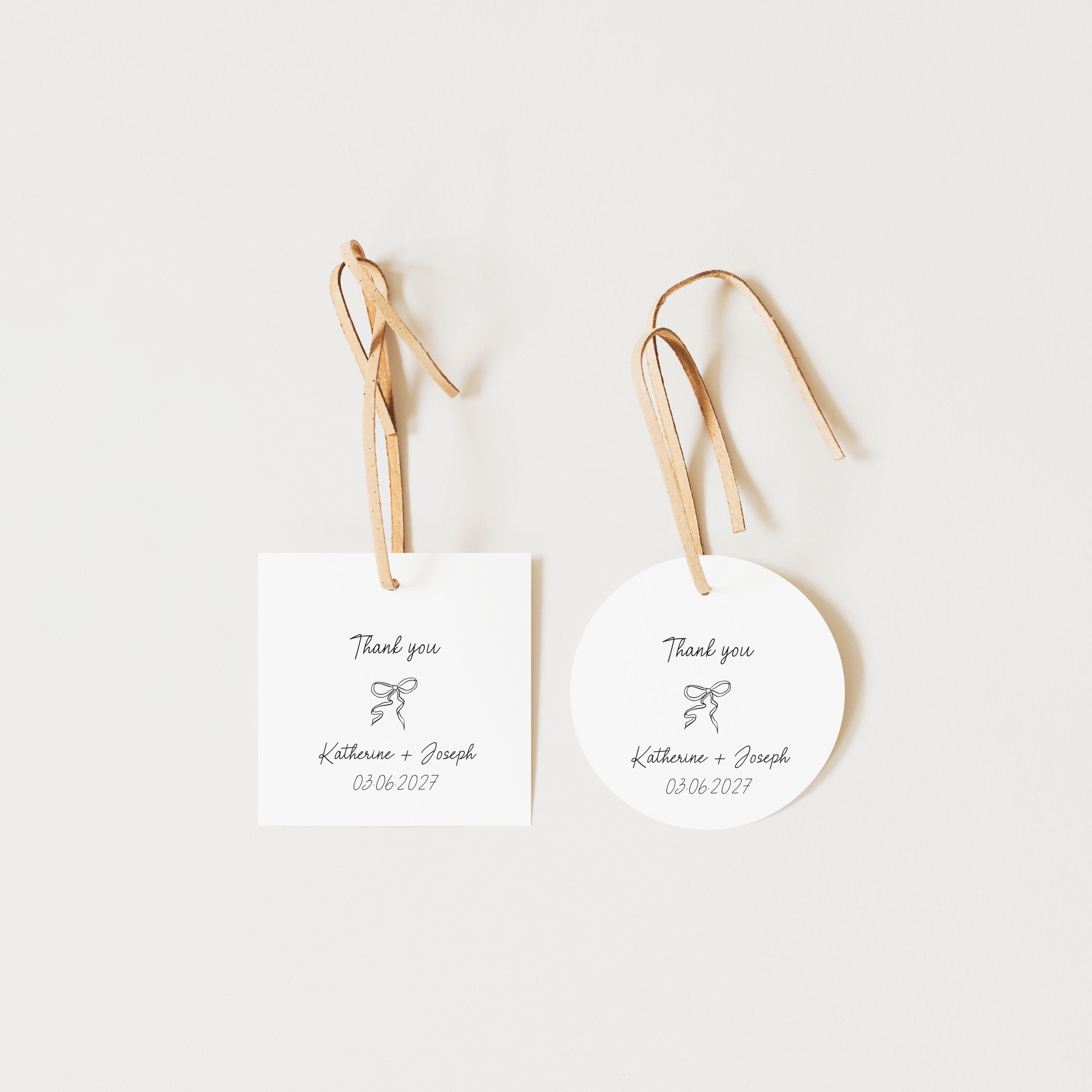 Two personalized wedding favor tags, one rectangular white card and one round white tag, both hanging from natural wood ribbons with printed 'Thank you' text and the names 'Katherine + Joseph' plus the date '03/06/2017'.