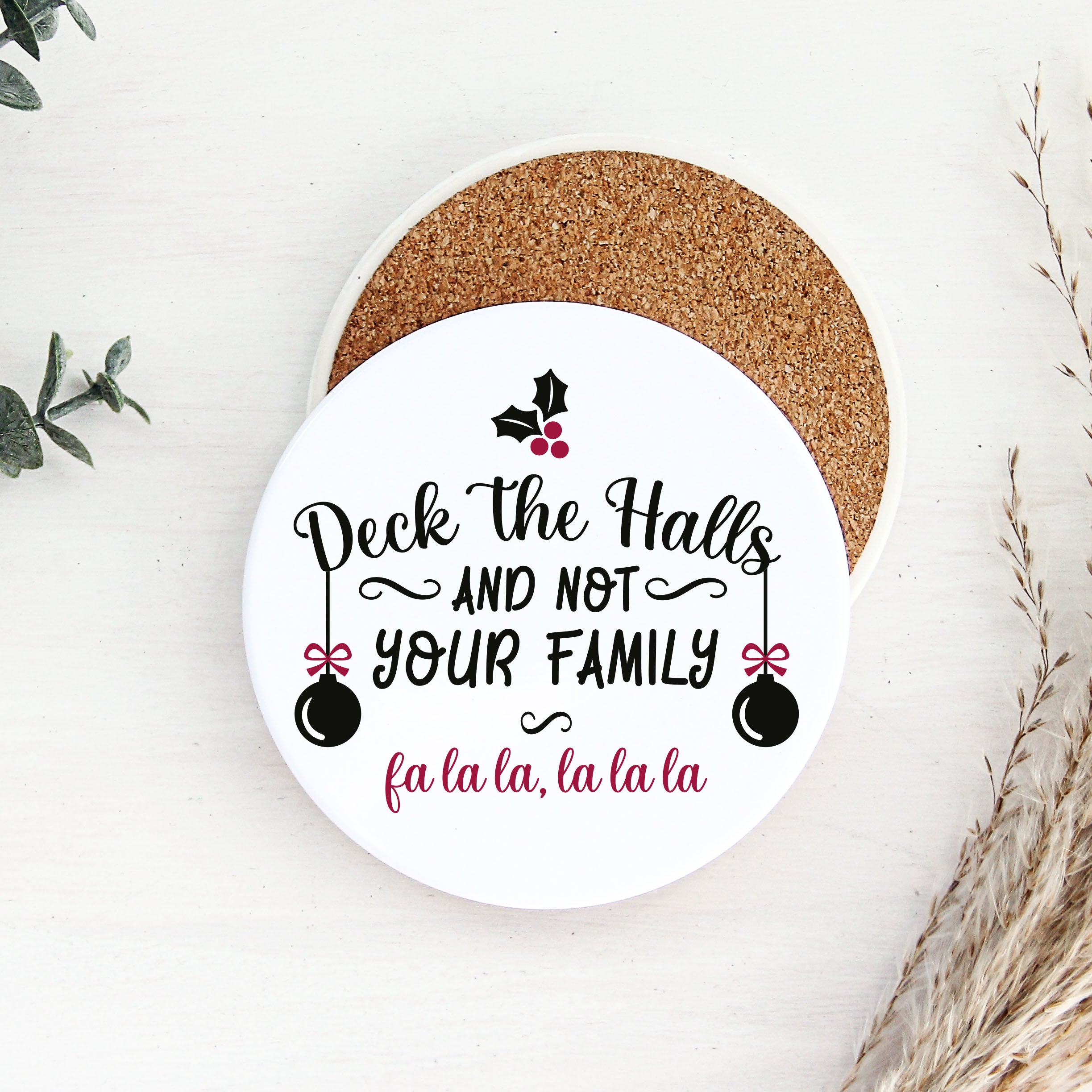 Round coaster with Christmas-themed text and decorations on a white surface.