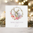 Christmas card with deer and floral wreath design on a blurred festive background