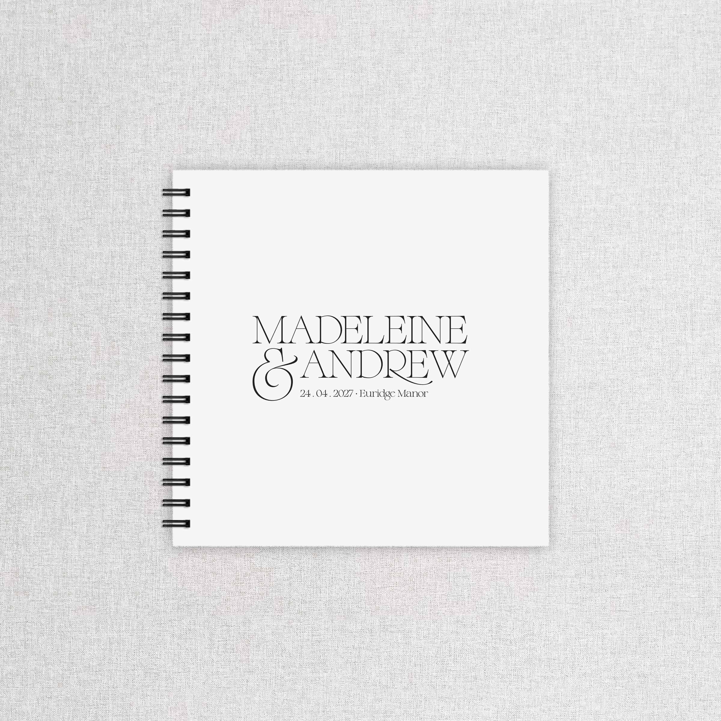 Spiral-bound wedding guestbook with 'Madeleine & Andrew' on a textured gray background