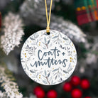 Decorative ornament with 'Coats + Matters' text on a floral pattern, hanging against a Christmas tree background.