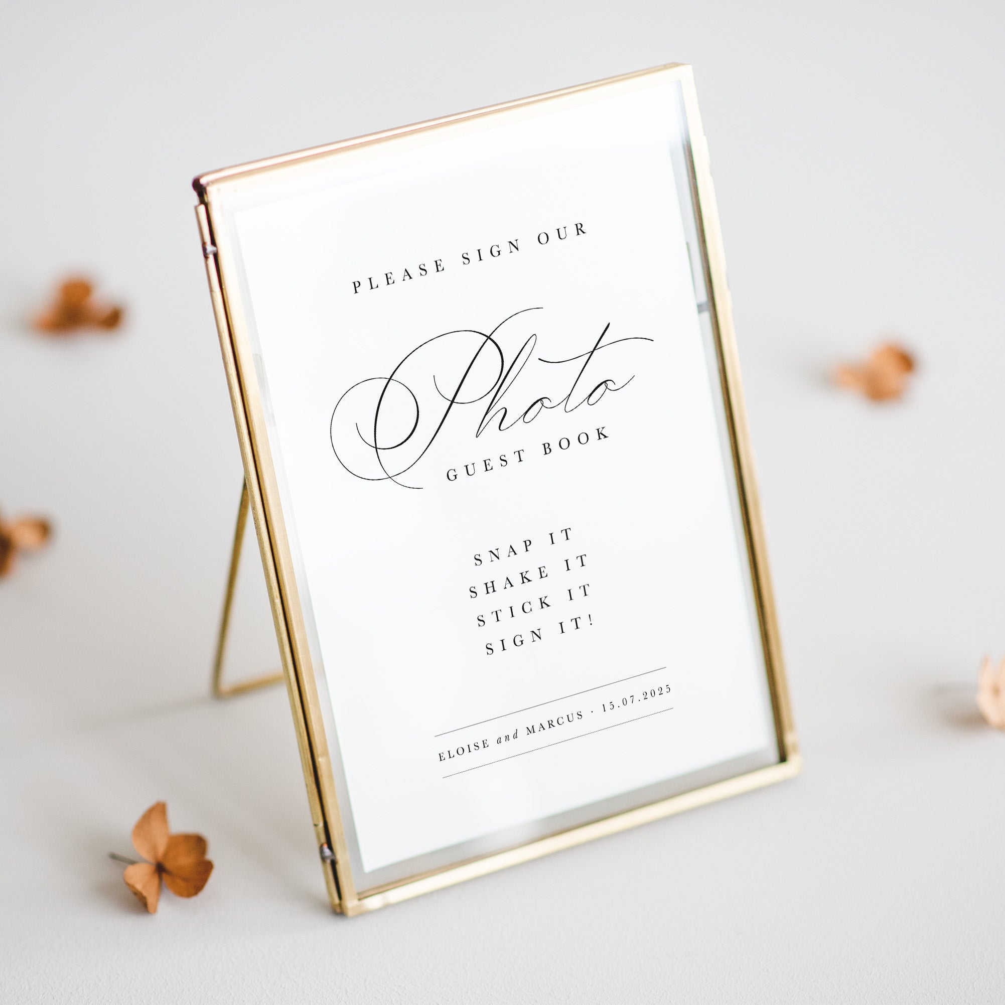Gold-framed sign inviting guests to sign a photo guest book on a light gray background.