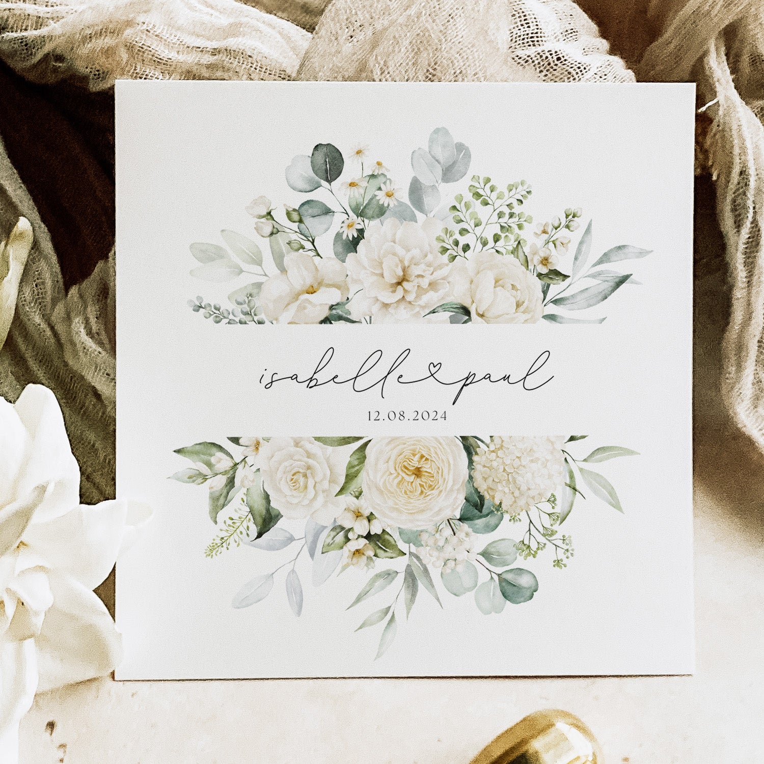 Floral design with text on a white card, surrounded by flowers and fabric.