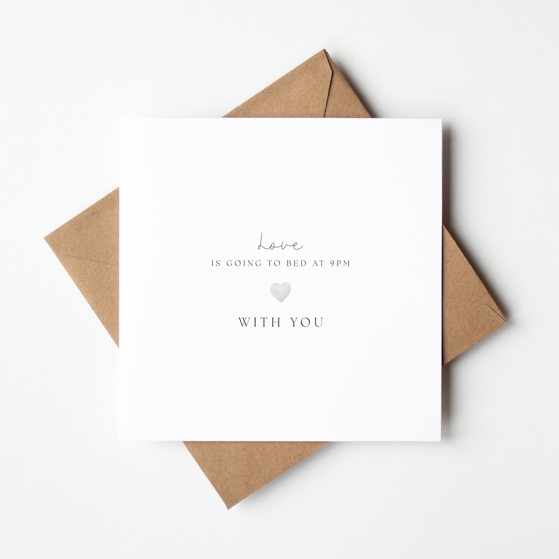 White card with text and a heart symbol on a brown envelope against a white background