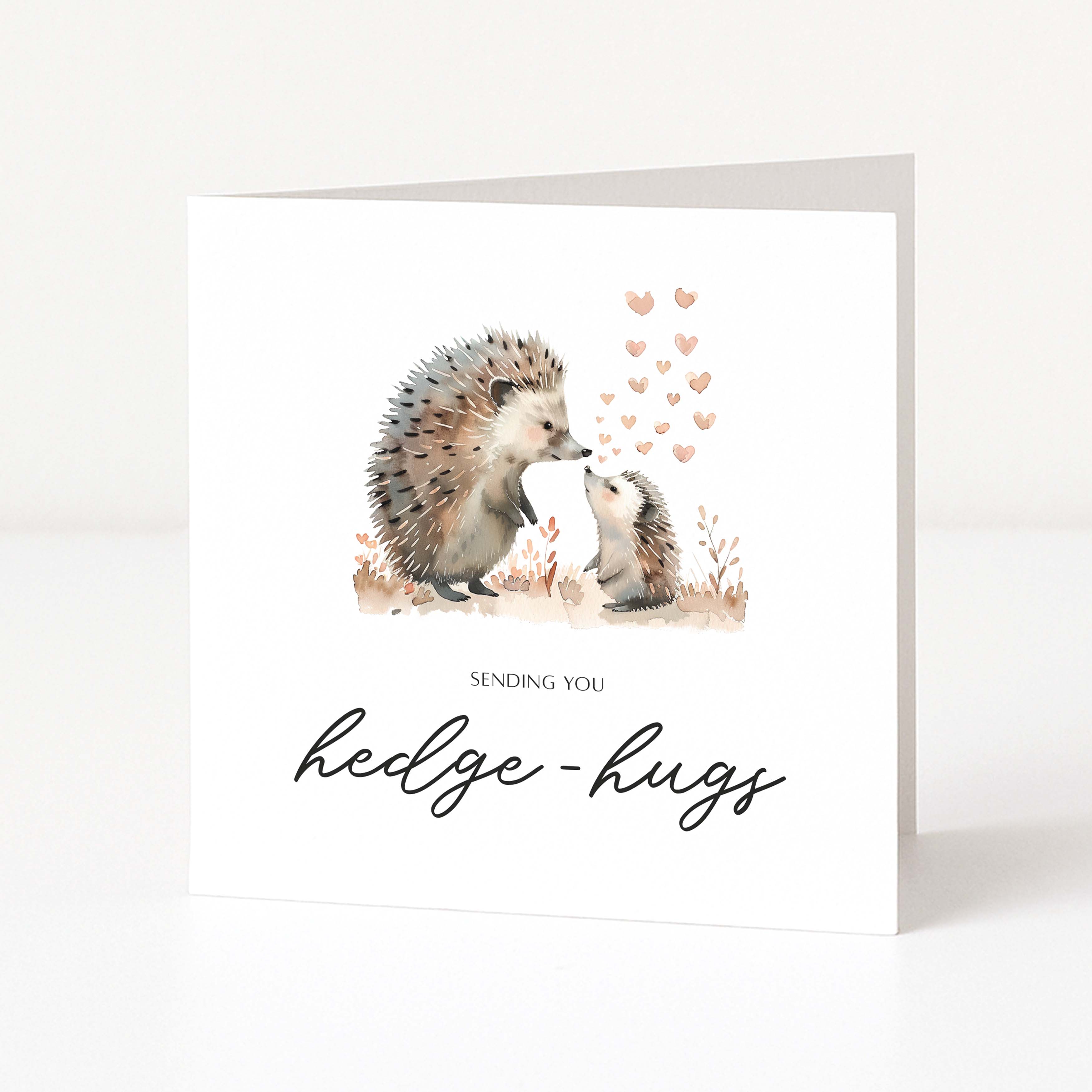 Greeting card with hedgehogs and text 'Sending you hedge-hugs' on a white background