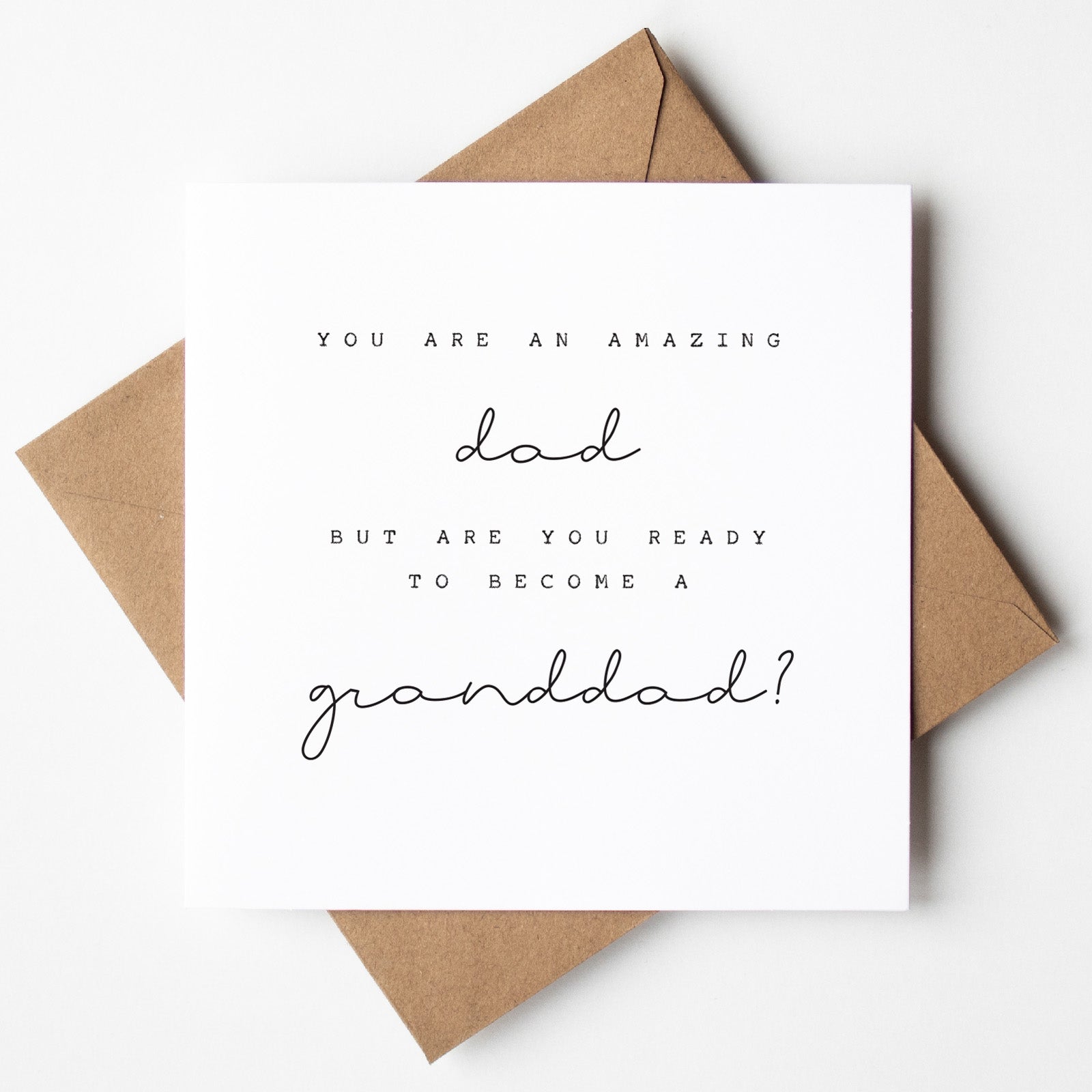 Greeting card with text 'You are an amazing dad but are you ready to become a granddad?' on a white background with brown envelope.