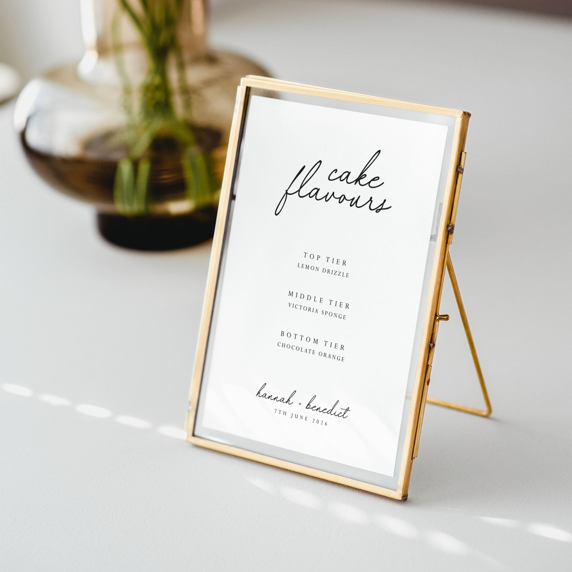Gold-framed sign with 'cake flavours' text on a white surface