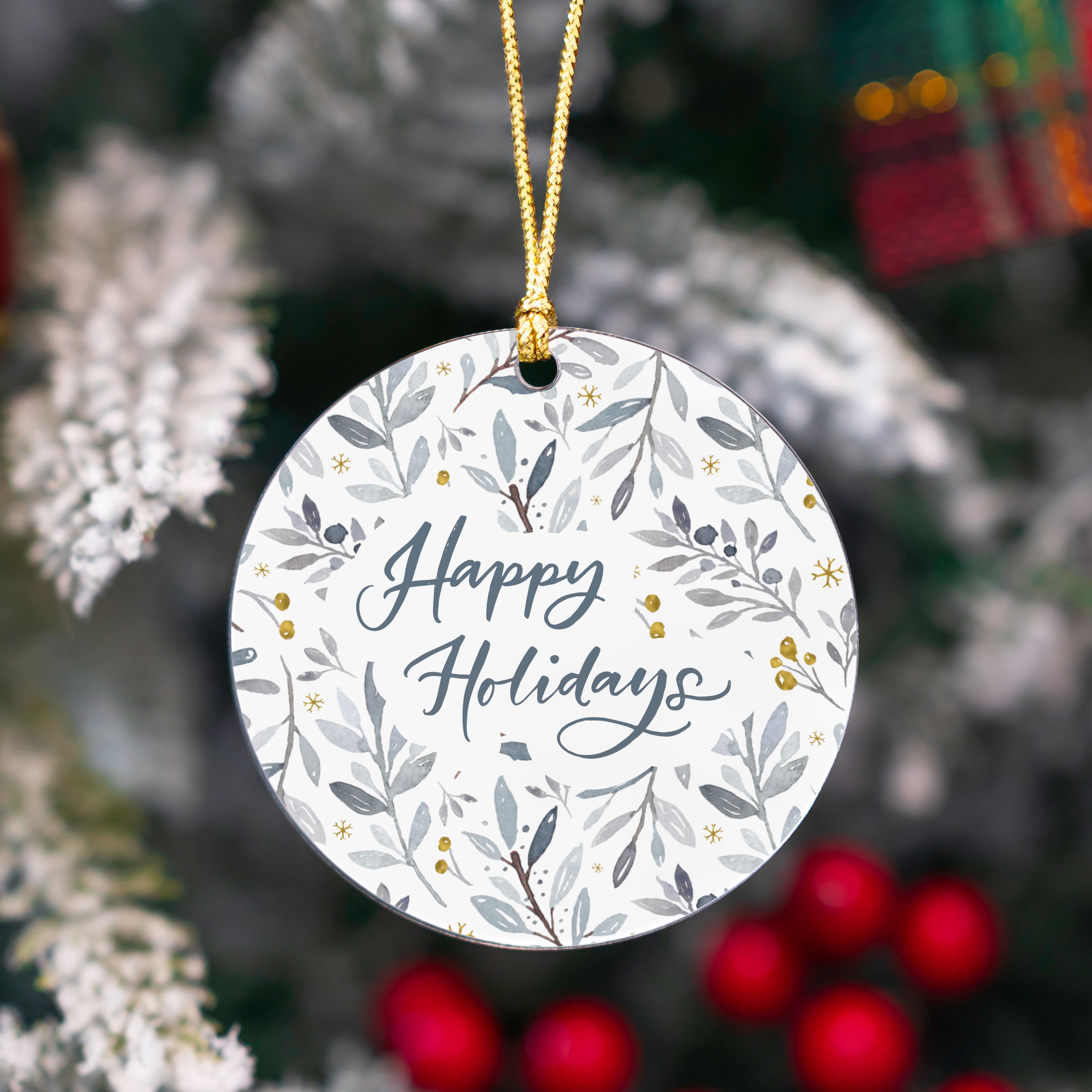 Round ornament with 'Happy Holidays' text and floral design, hanging on a tree.