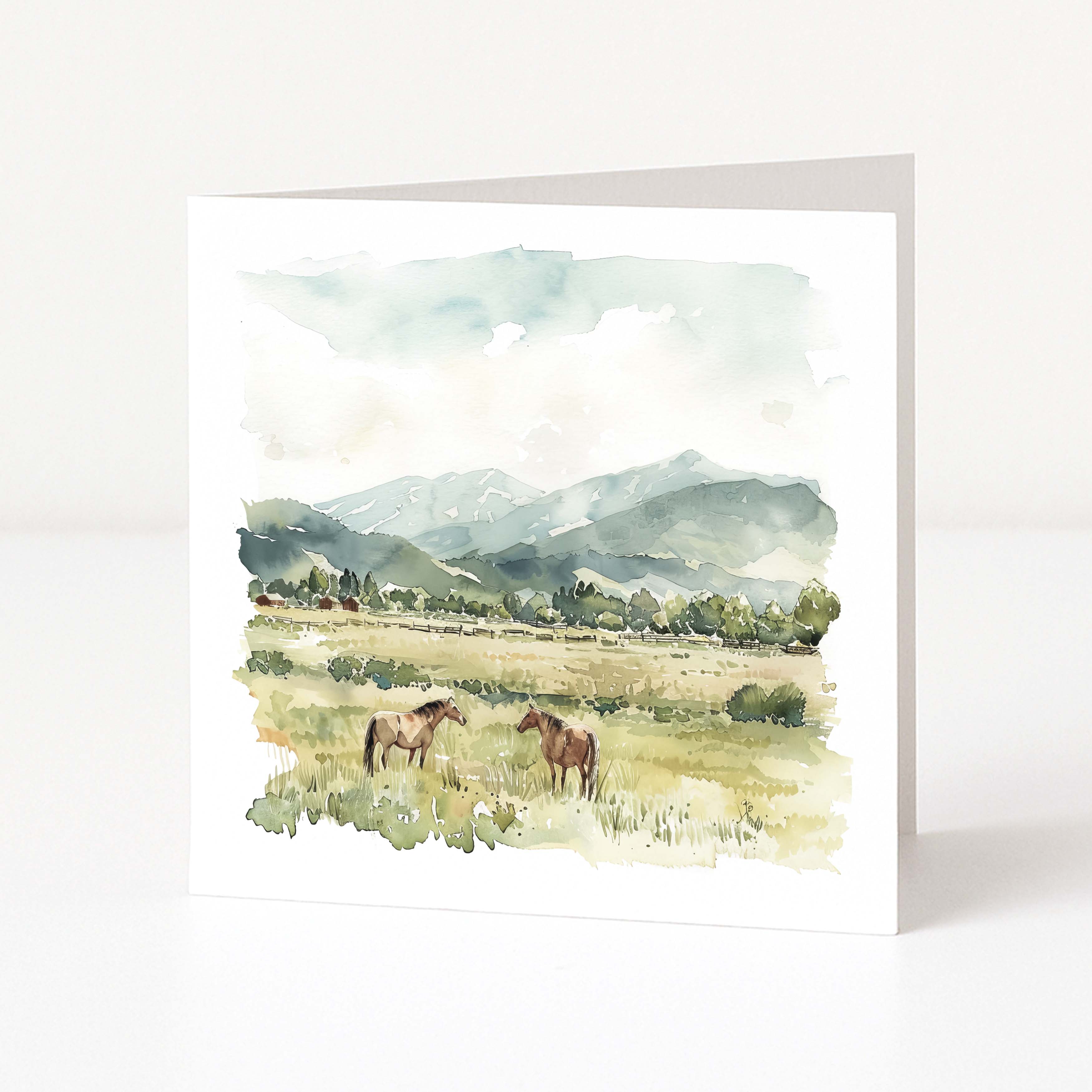 Greeting card with watercolor illustration of two horses in a field with mountains in the background.