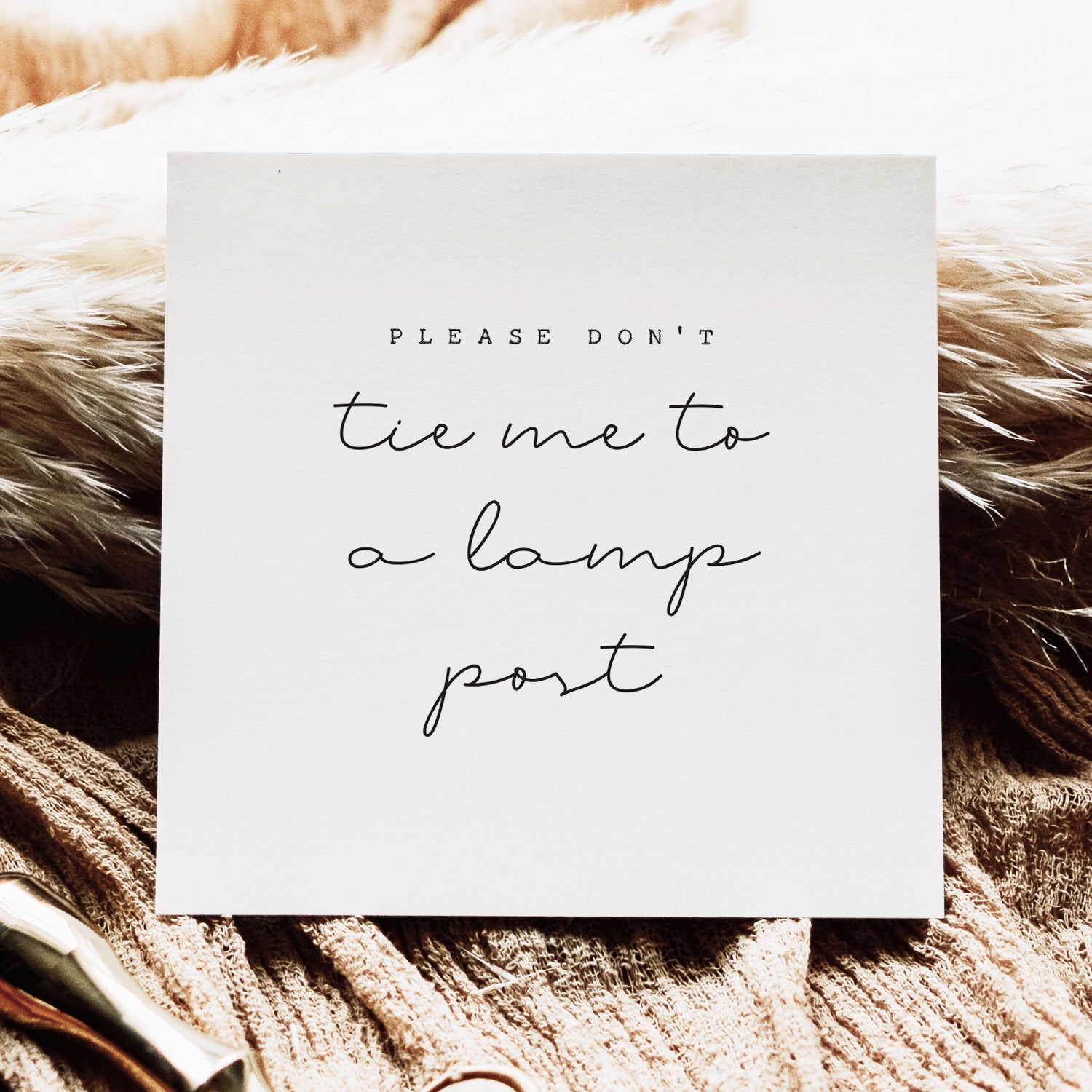 White card with text 'Please don't tie me to a lamp post' on a textured brown background