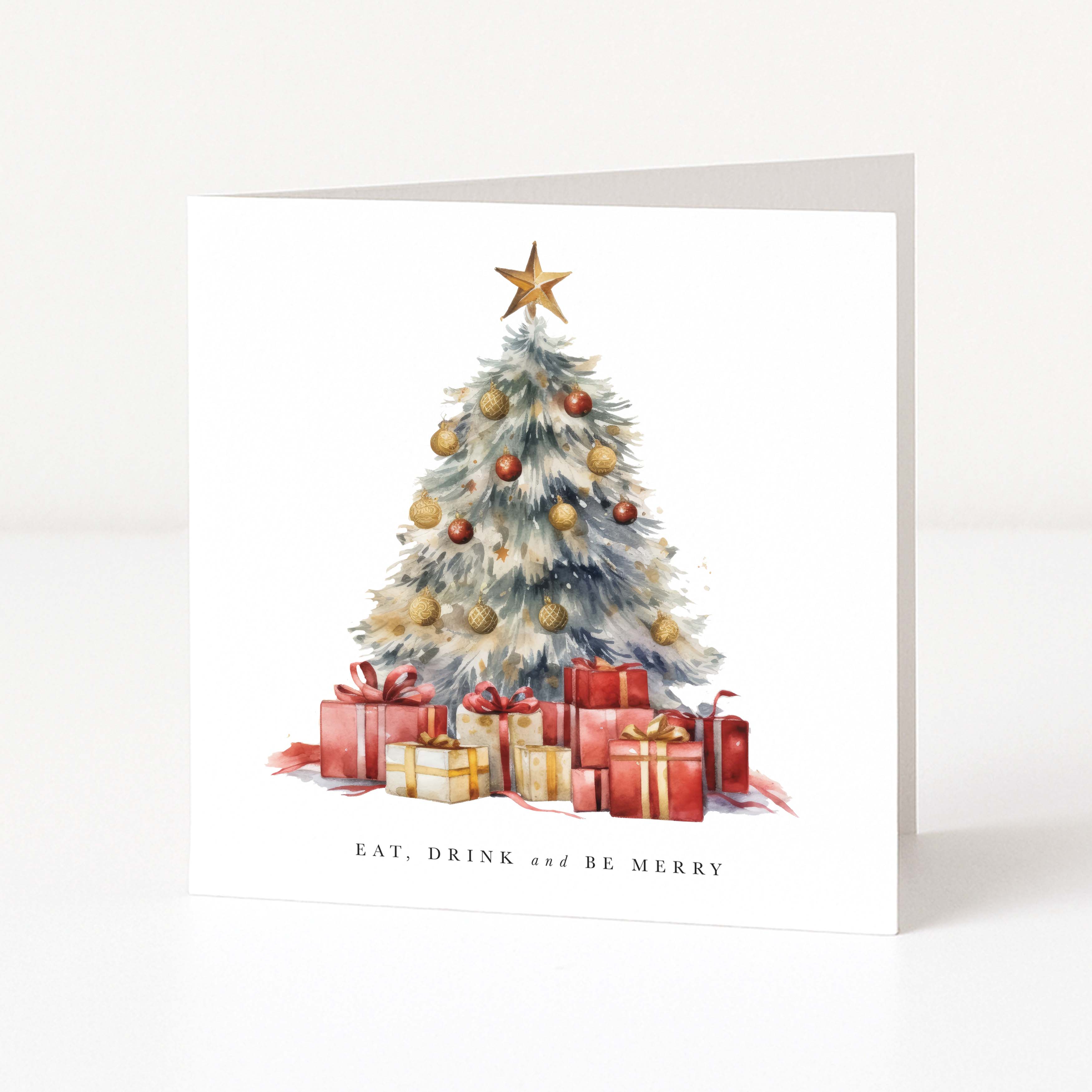A square white Christmas greeting card standing upright on a light surface. The front features a watercolor-style decorated tree with a gold star, red and gold ornaments, wrapped presents, and the text 'EAT, DRINK and BE MERRY'.