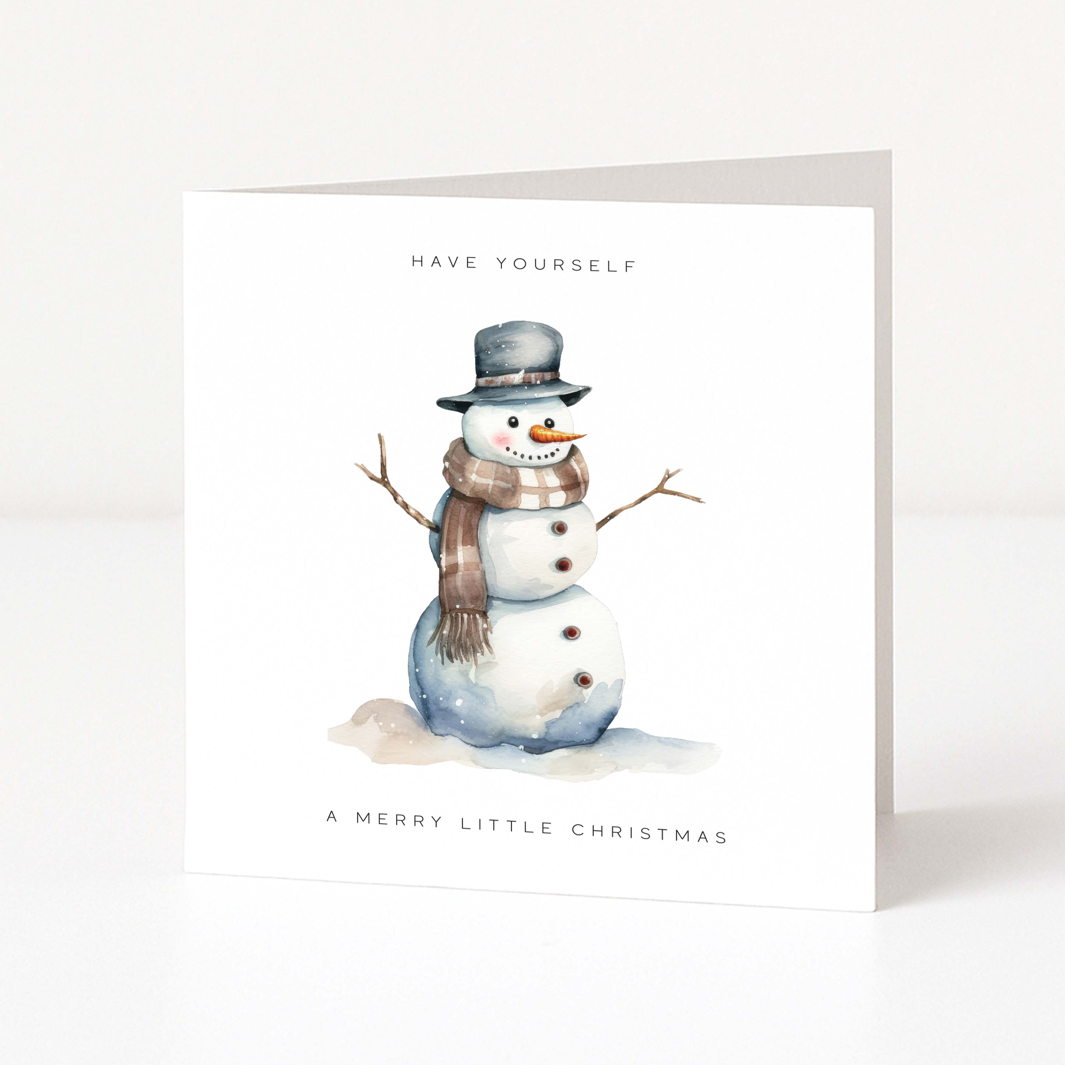 A white Christmas greeting card featuring a watercolor illustration of a snowman wearing a gray hat and brown scarf, with the text 'HAVE YOURSELF' above and 'A MERRY LITTLE CHRISTMAS' below, shown standing against a light neutral background.