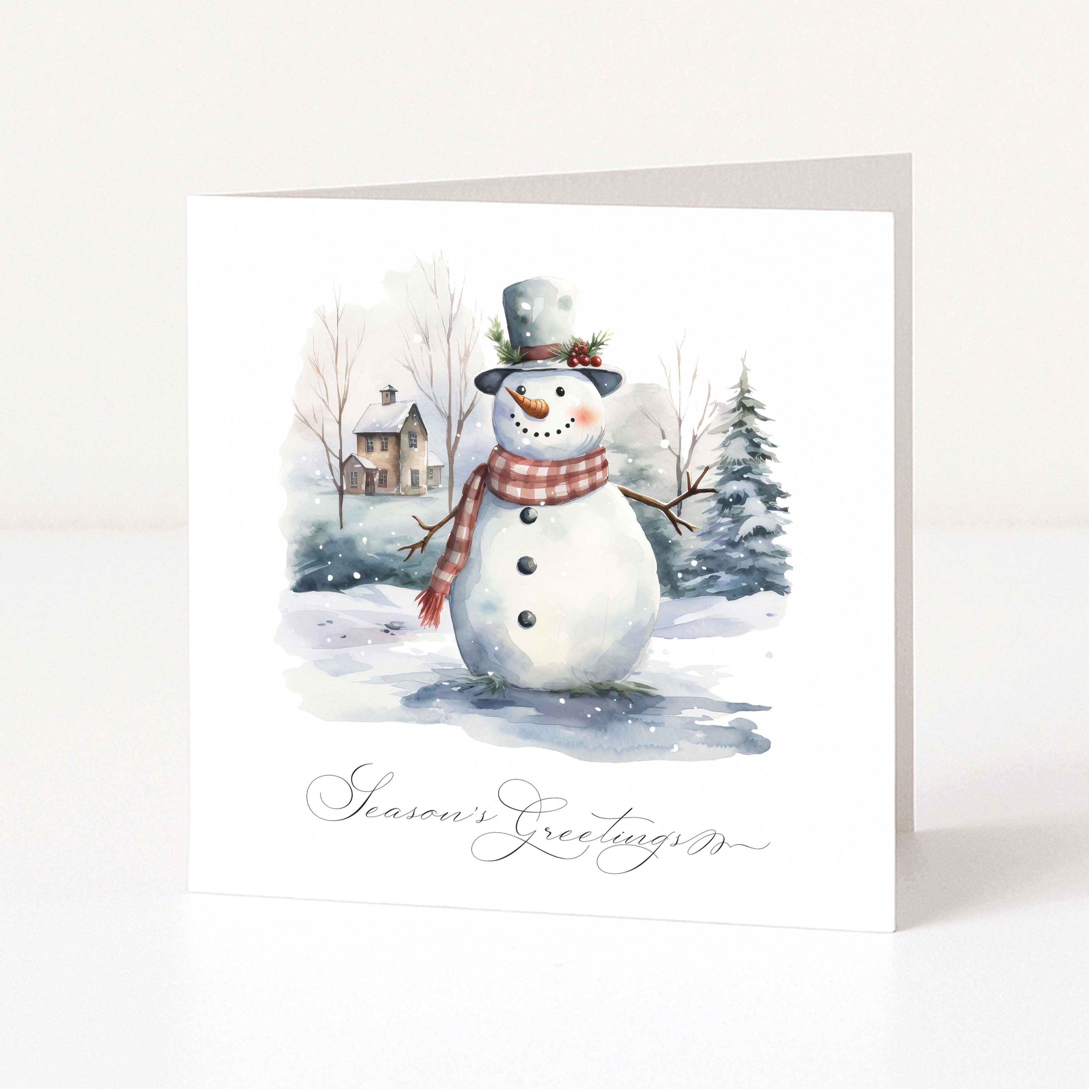 A square white Christmas greeting card standing upright, printed with a watercolour winter scene featuring a snowman wearing a grey top hat and red plaid scarf, with the text 'Season's Greetings' at the bottom.
