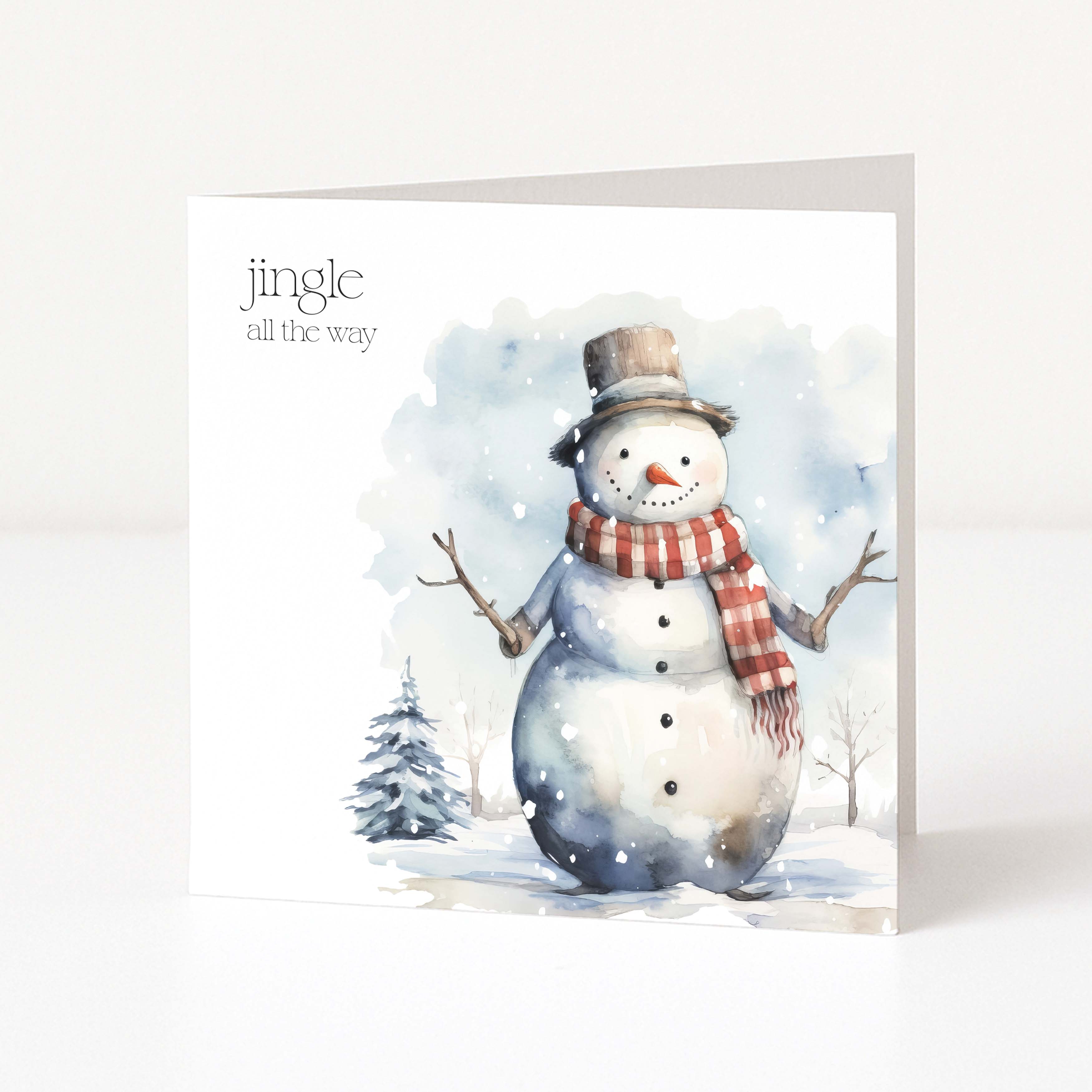 A square Christmas greeting card featuring a watercolour illustration of a snowman wearing a brown top hat and a red-and-white striped scarf, with the text 'jingle all the way' on a white background.