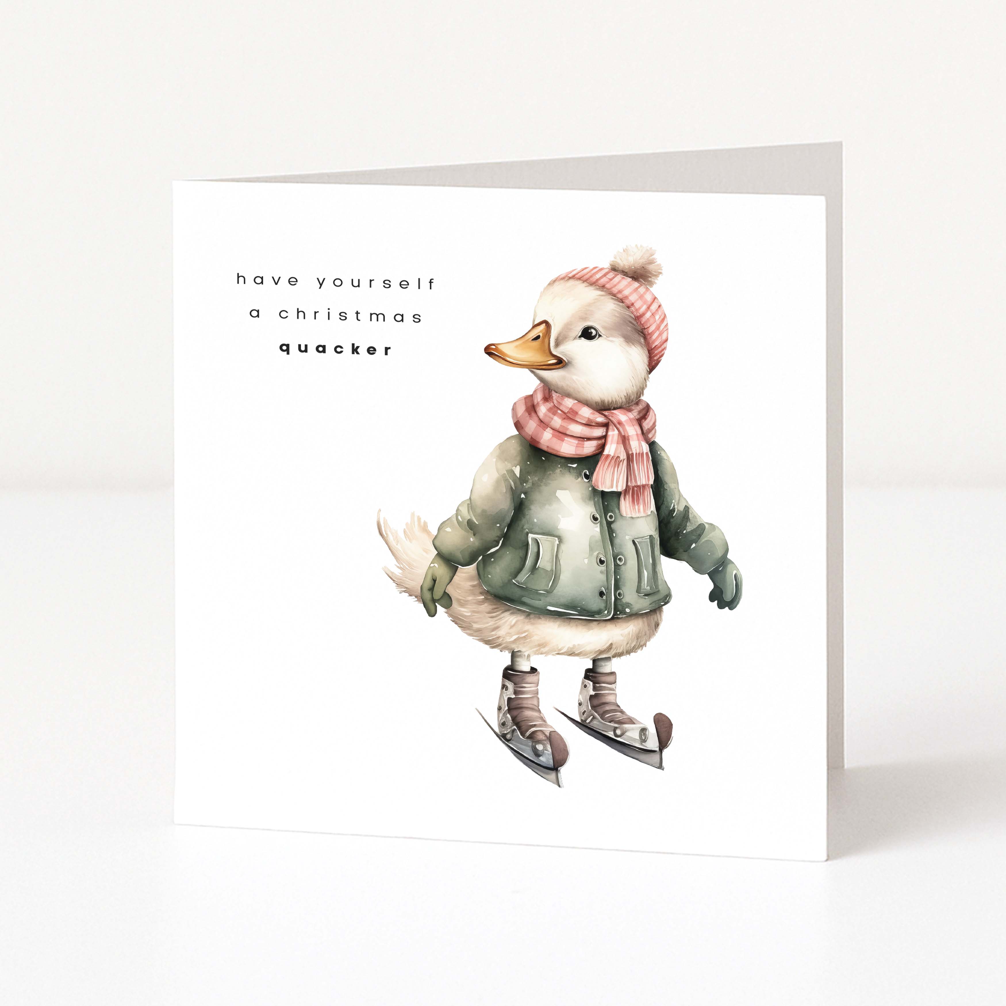 A white Christmas greeting card featuring an illustration of a duck wearing winter clothing and ice skates, with the text 'have yourself a christmas quacker' printed on the front.