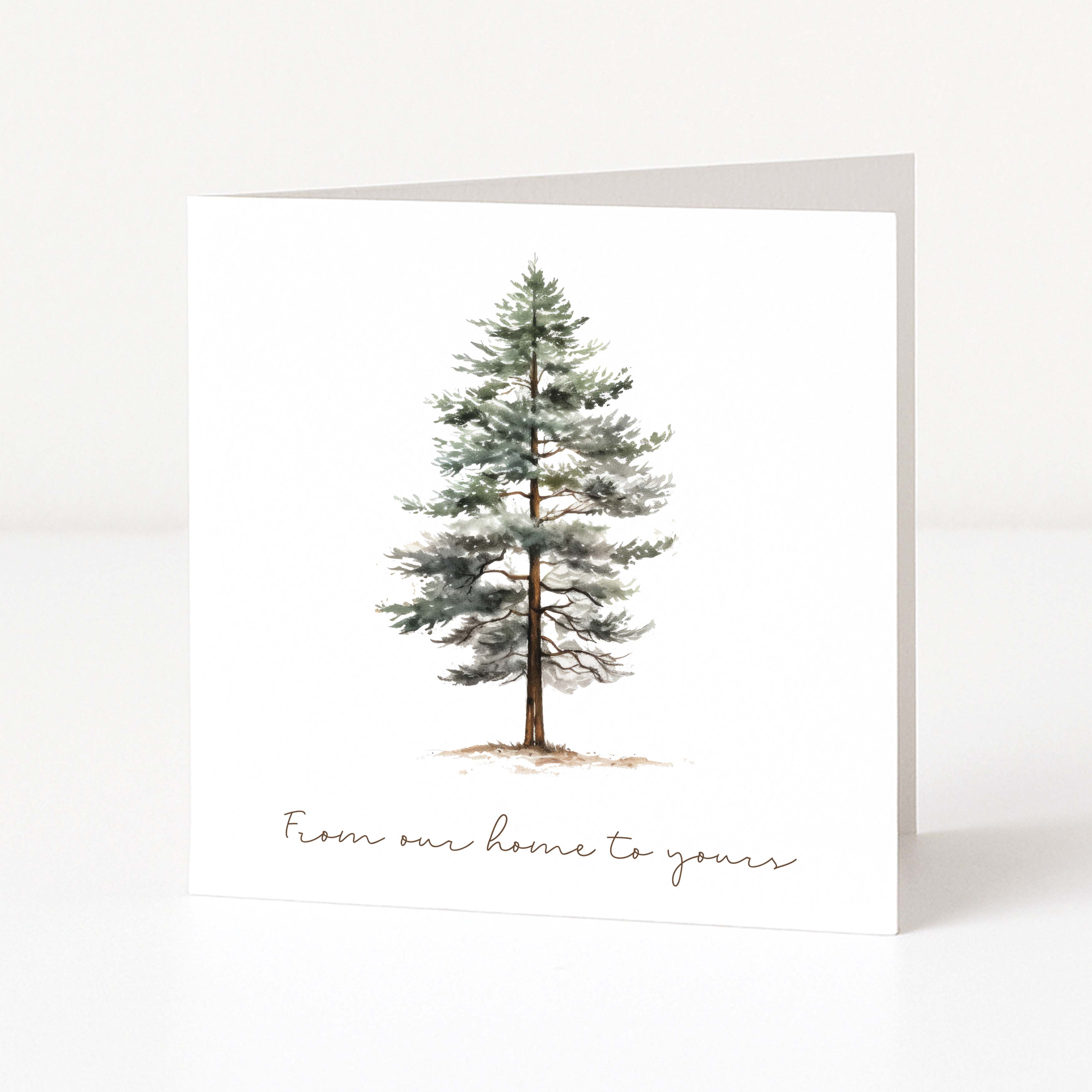A white Christmas greeting card featuring a watercolour illustration of a snow-dusted pine tree and the printed phrase 'From our home to yours' in a delicate script at the bottom.
