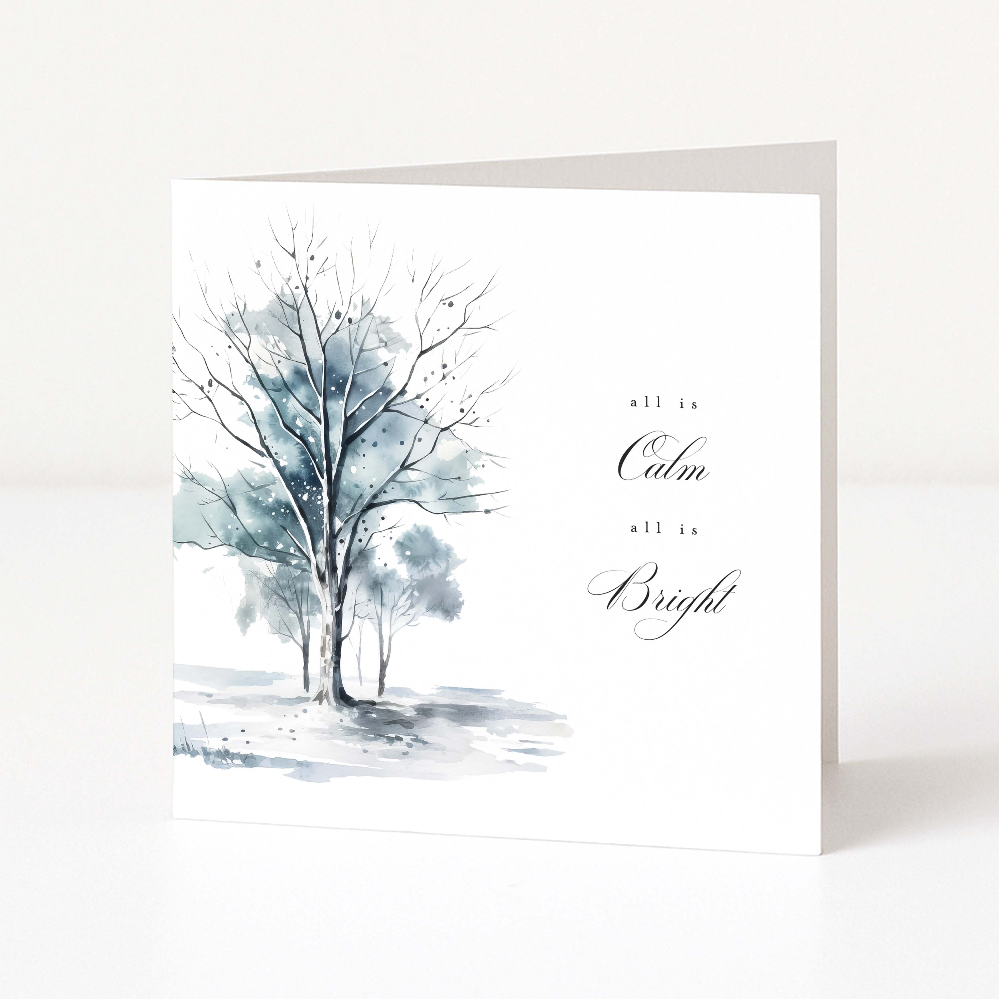 A white Christmas greeting card with a watercolour painting of two leafless trees in soft blue-grey tones and the words 'all is Calm all is Bright' in black script, shown standing against a white background.