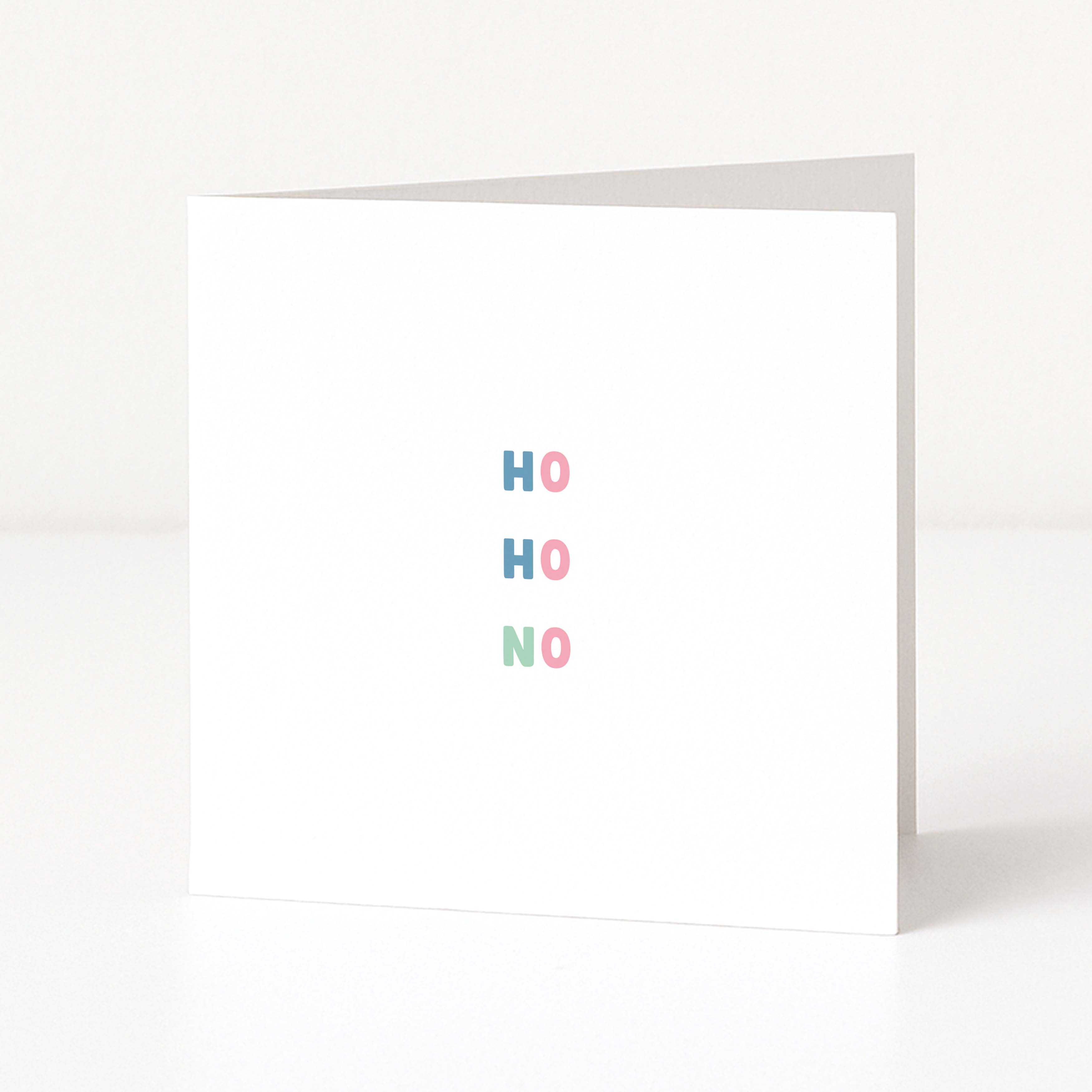 A white anti-Christmas greeting card standing upright on a white surface, with the words 'HO HO NO' spelled out vertically in pastel blue, pink, and mint green letters.