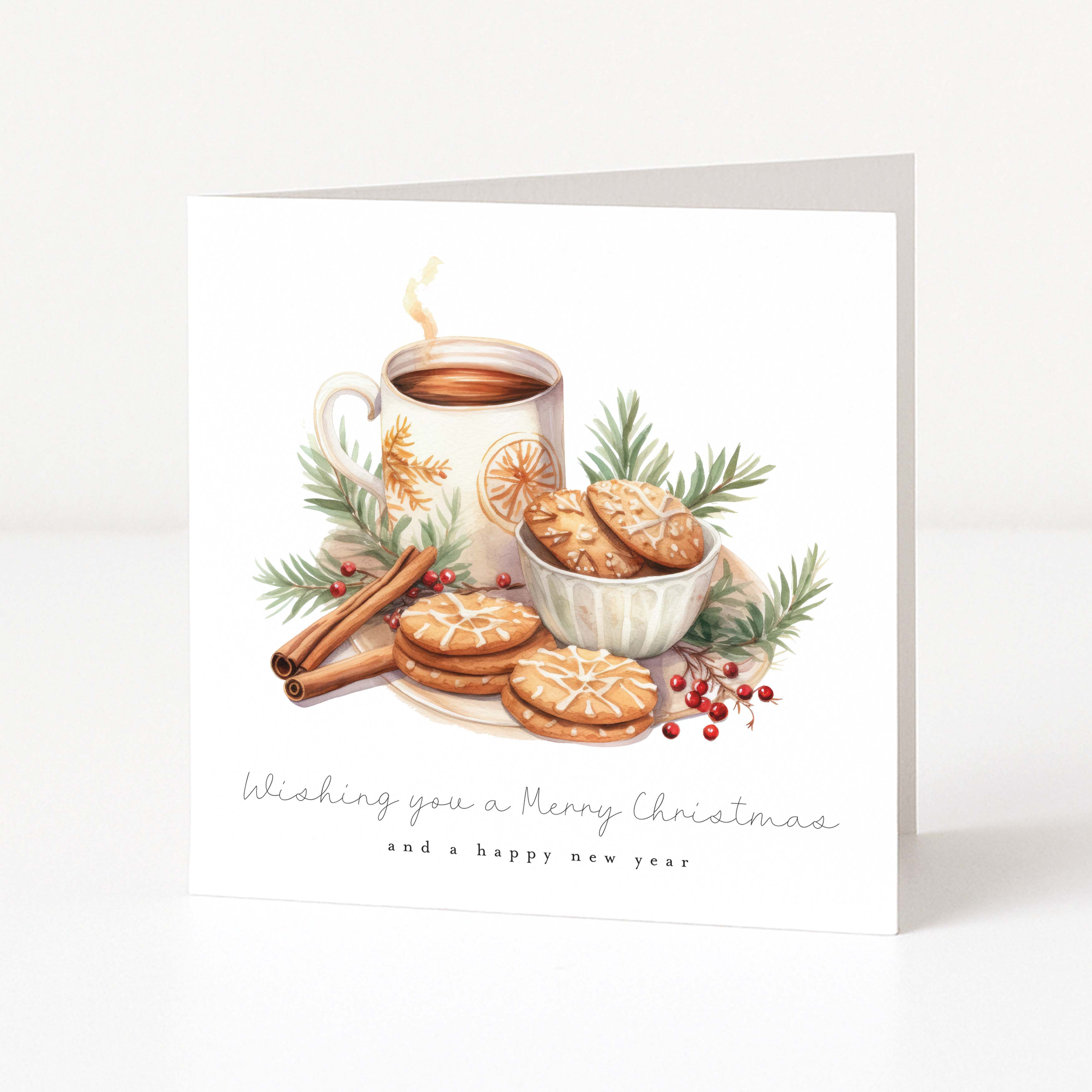A square white Christmas greeting card standing upright on a light surface. The front features an illustrated holiday still life with a mug of hot drink, cookies, cinnamon sticks, greenery, and red berries, plus the text 'Wishing you a Merry Christmas and a happy new year'.