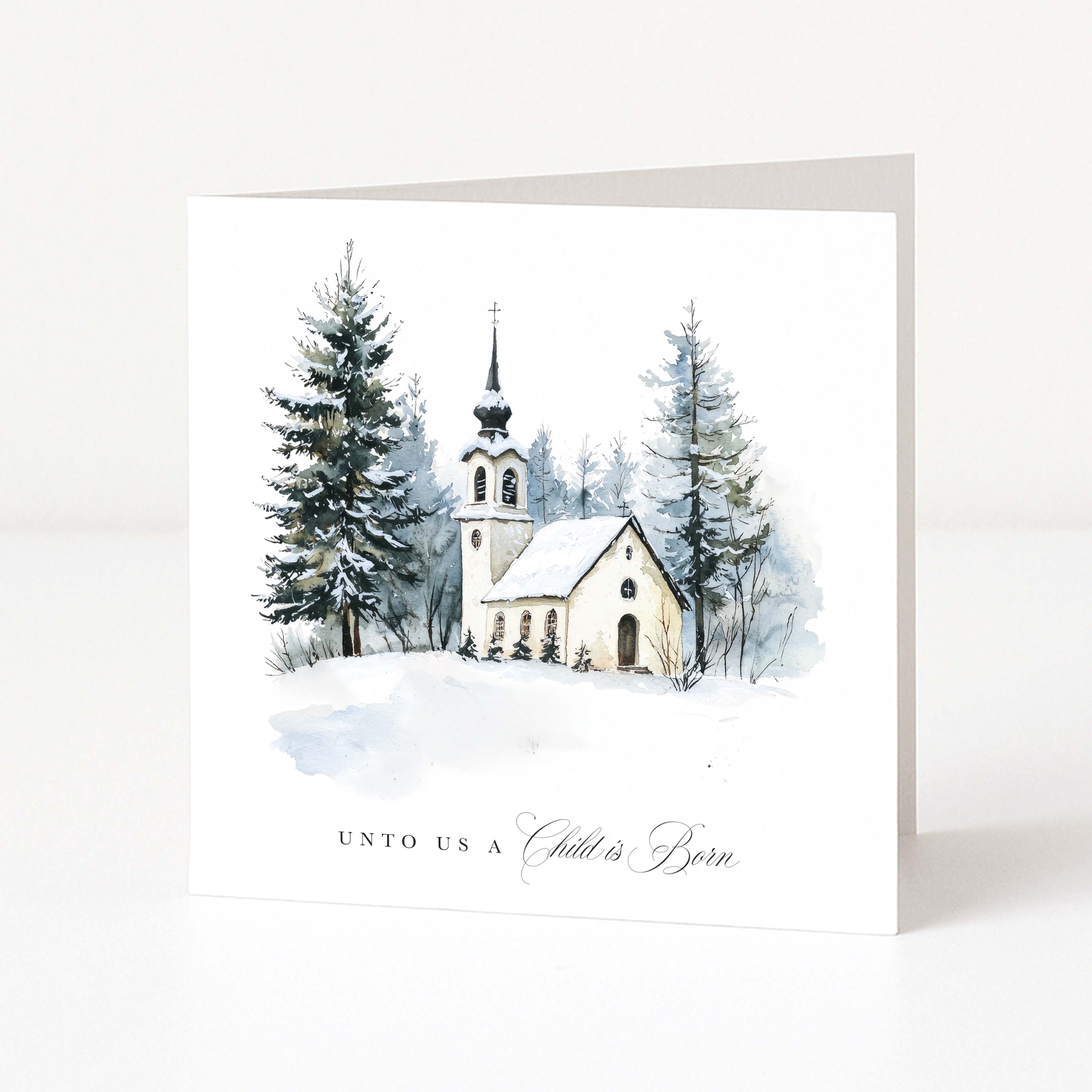 A white Christmas greeting card showing a watercolour church and surrounding forest scene and "Unto us a child is born" text beneath