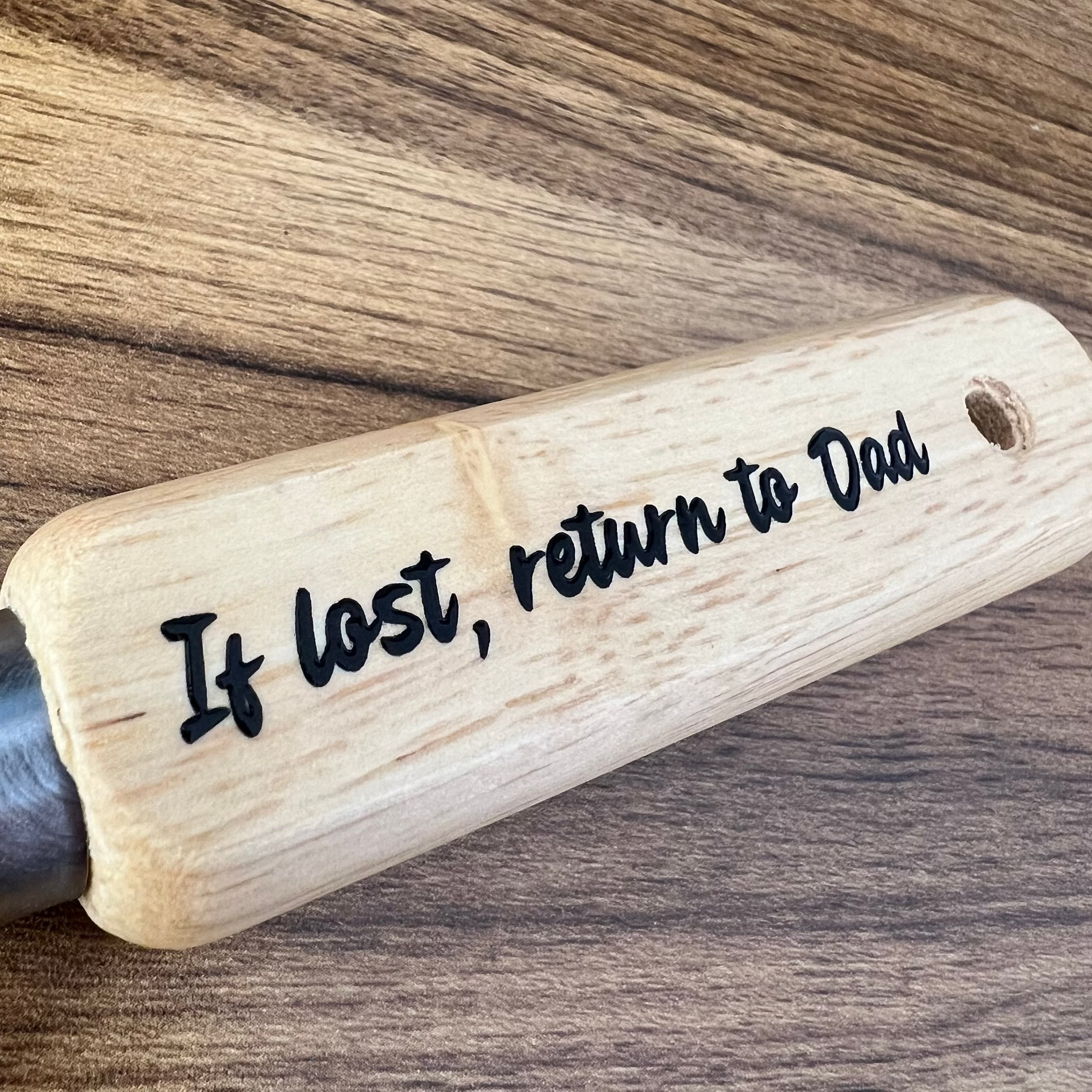 Wooden paddle with engraved text on a wooden surface