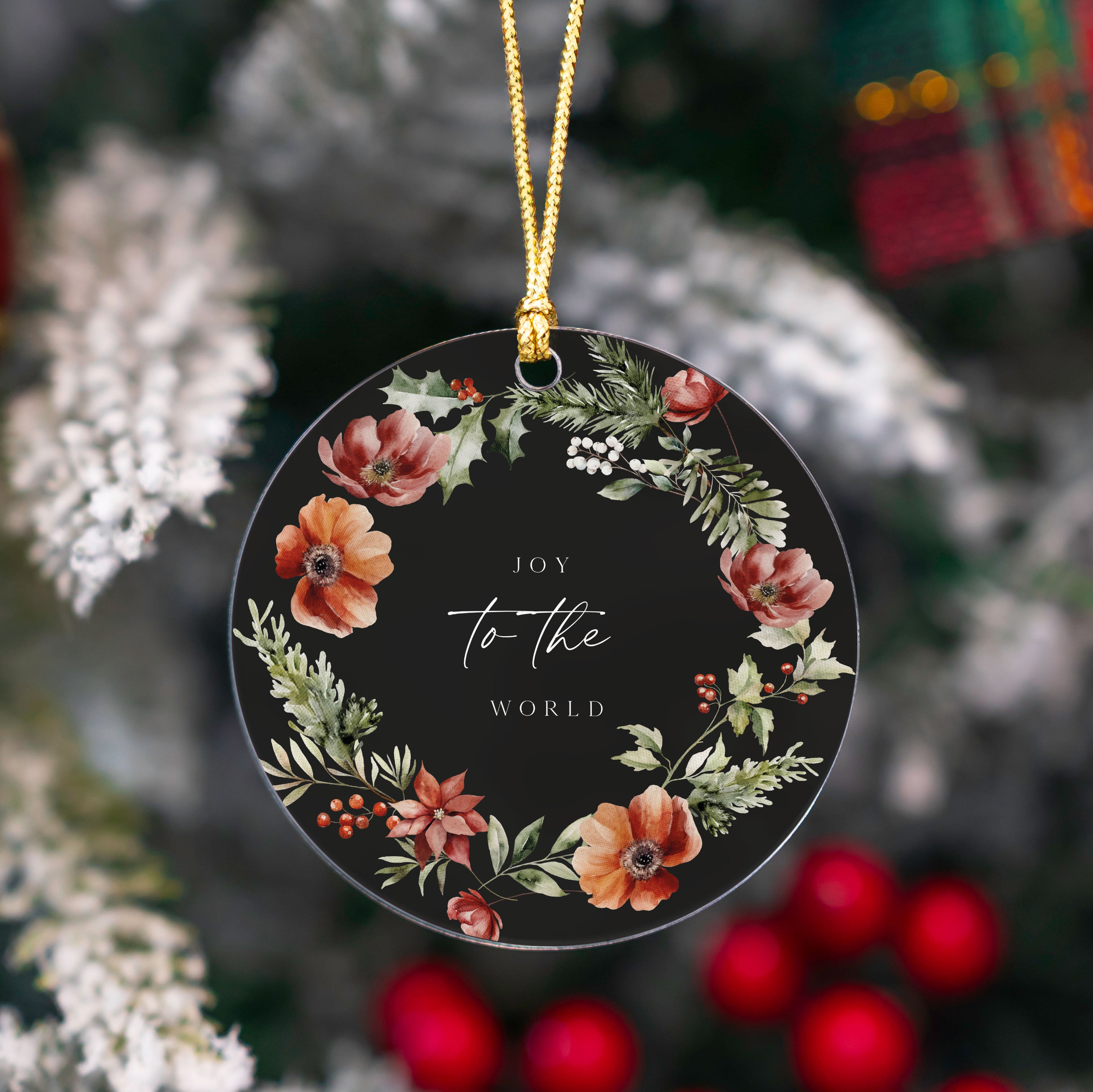 Decorative Christmas ornament with floral design and 'Joy to the World' text on a black background, hanging against a festive background.