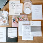 Collection of wedding invitations and stationery items on a wooden surface