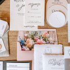 Wedding invitation set with floral design on a wooden surface