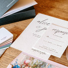 Wedding invitation card with 'alice & jamie' on a wooden surface