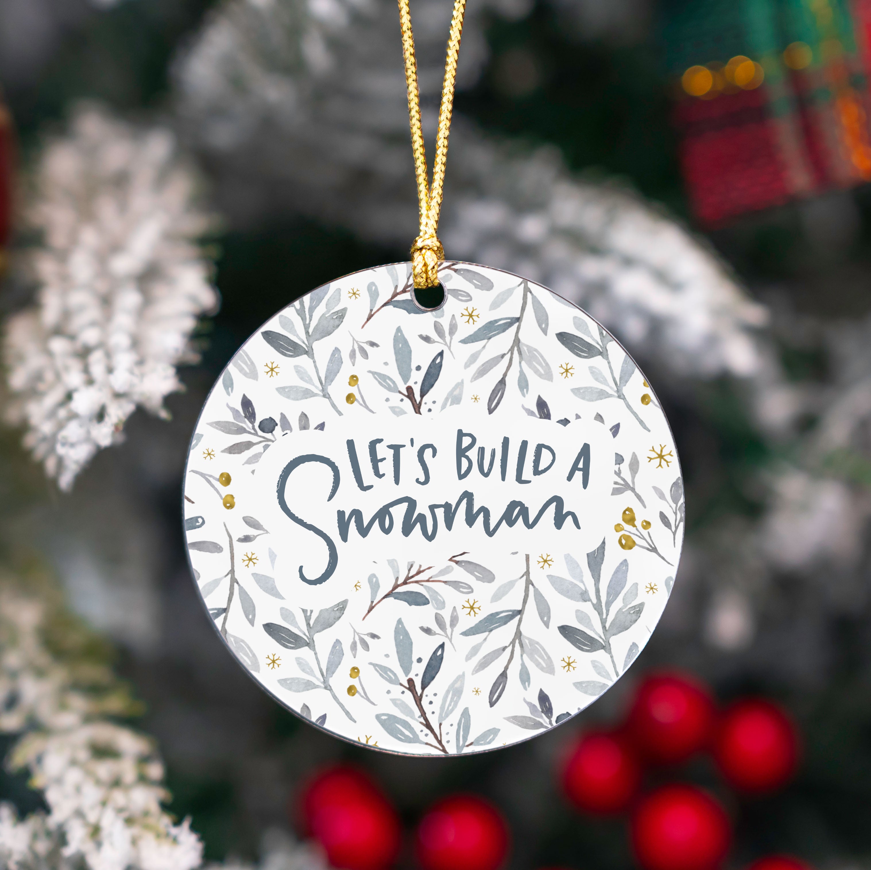 Decorative Christmas ornament with 'Let's Build a Snowman' text on a floral patterned background.