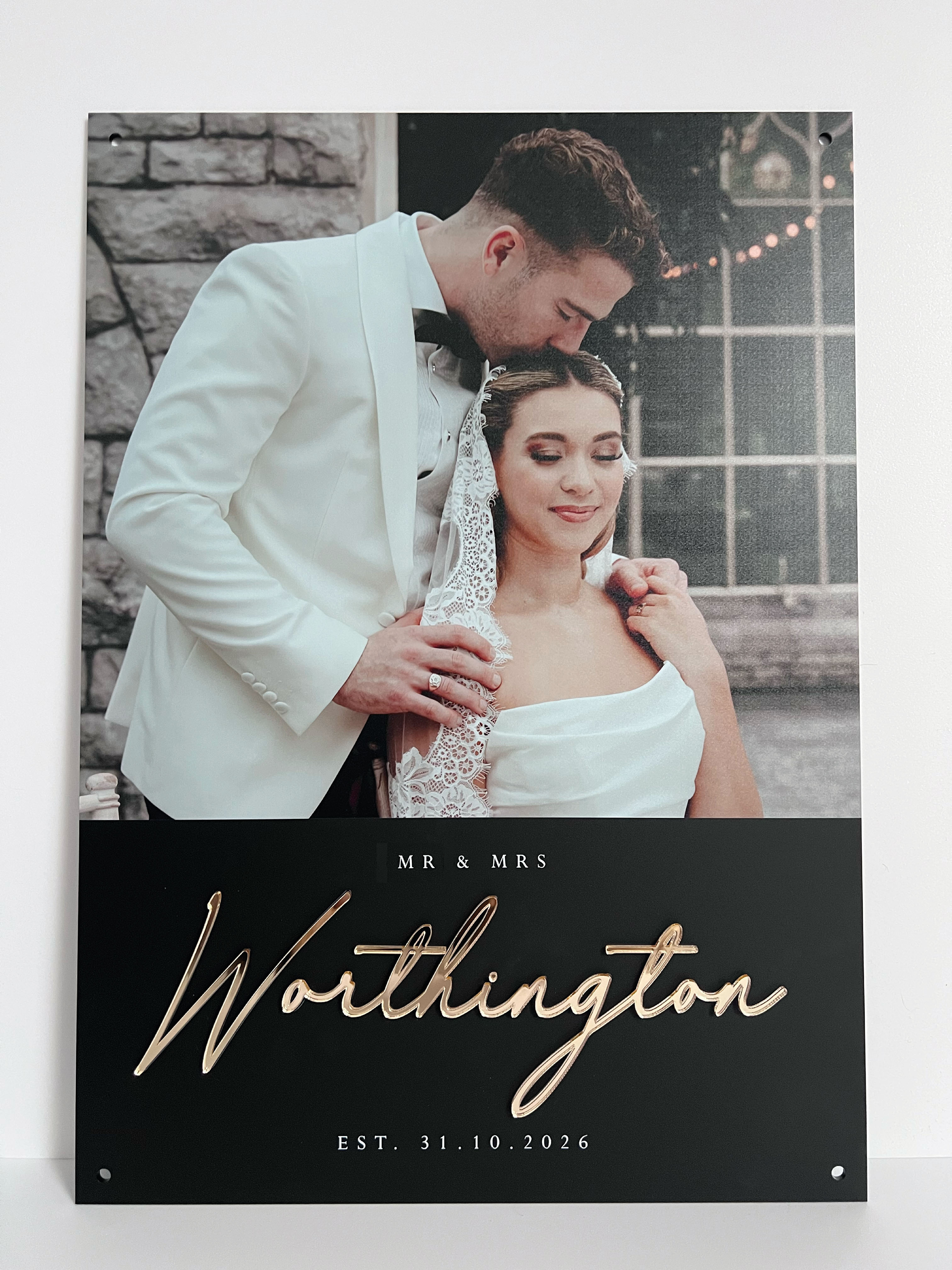 Wedding photo on black acrylic of a couple with 'MR & MRS Worthington' gold text on a black background
