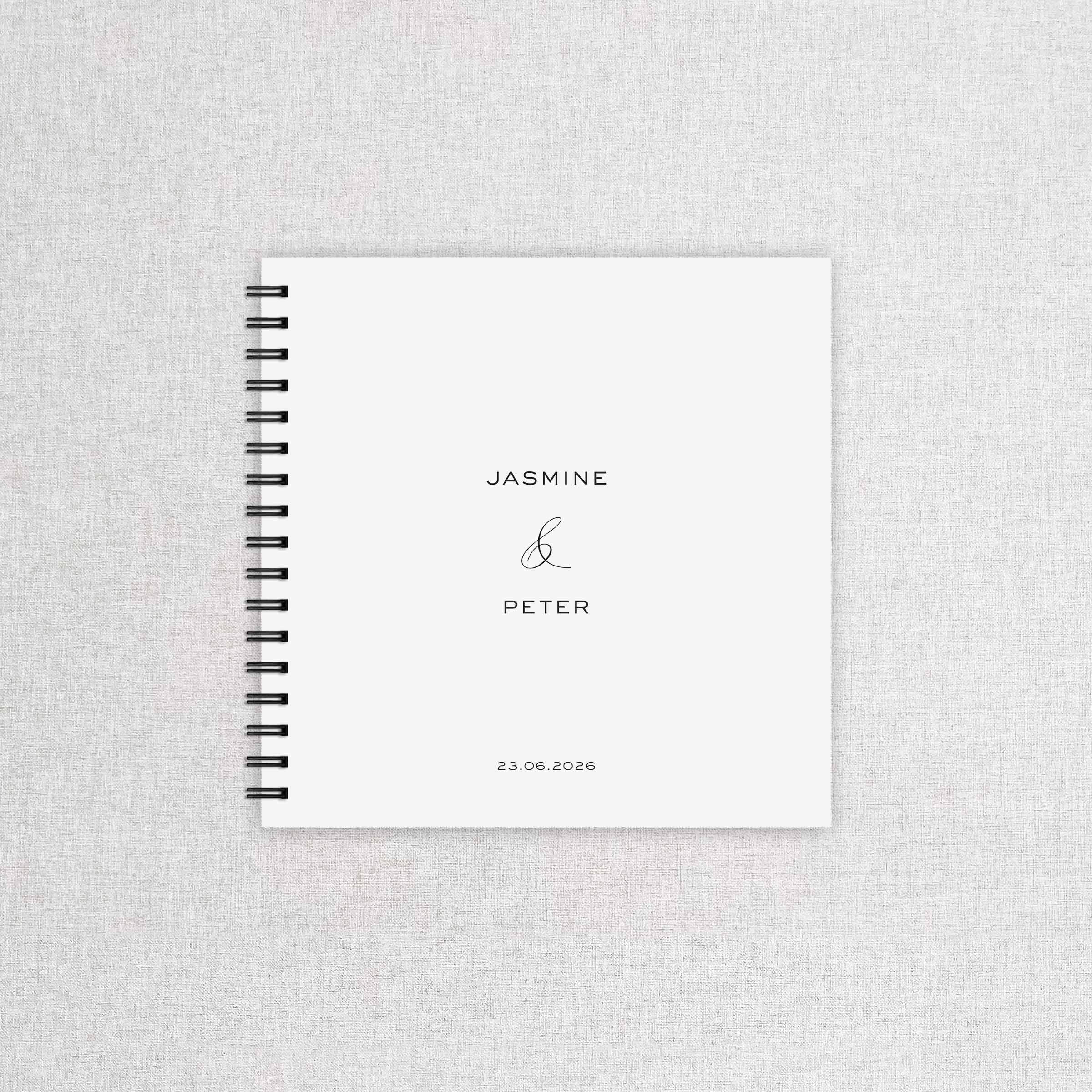 Spiral-bound notebook with 'Jasmine & Peter' and a date on a textured gray background