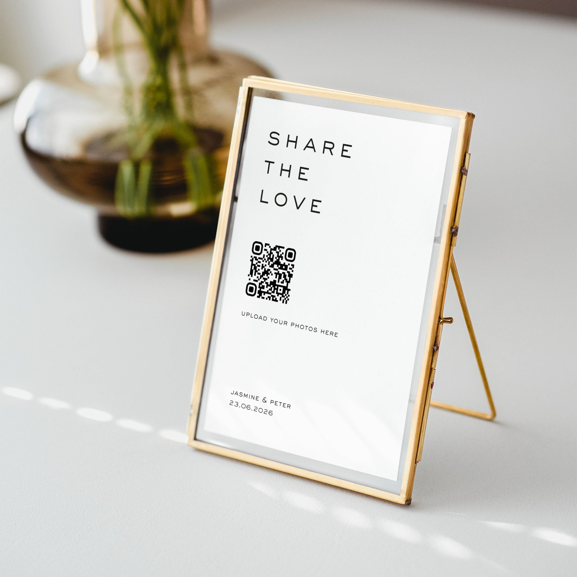 Gold frame with a photo sharing sign including QR code and text on a white surface for wedding reception
