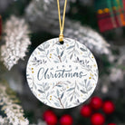 Round Christmas ornament with 'Merry Christmas' text and leaf pattern, hanging against a festive background.