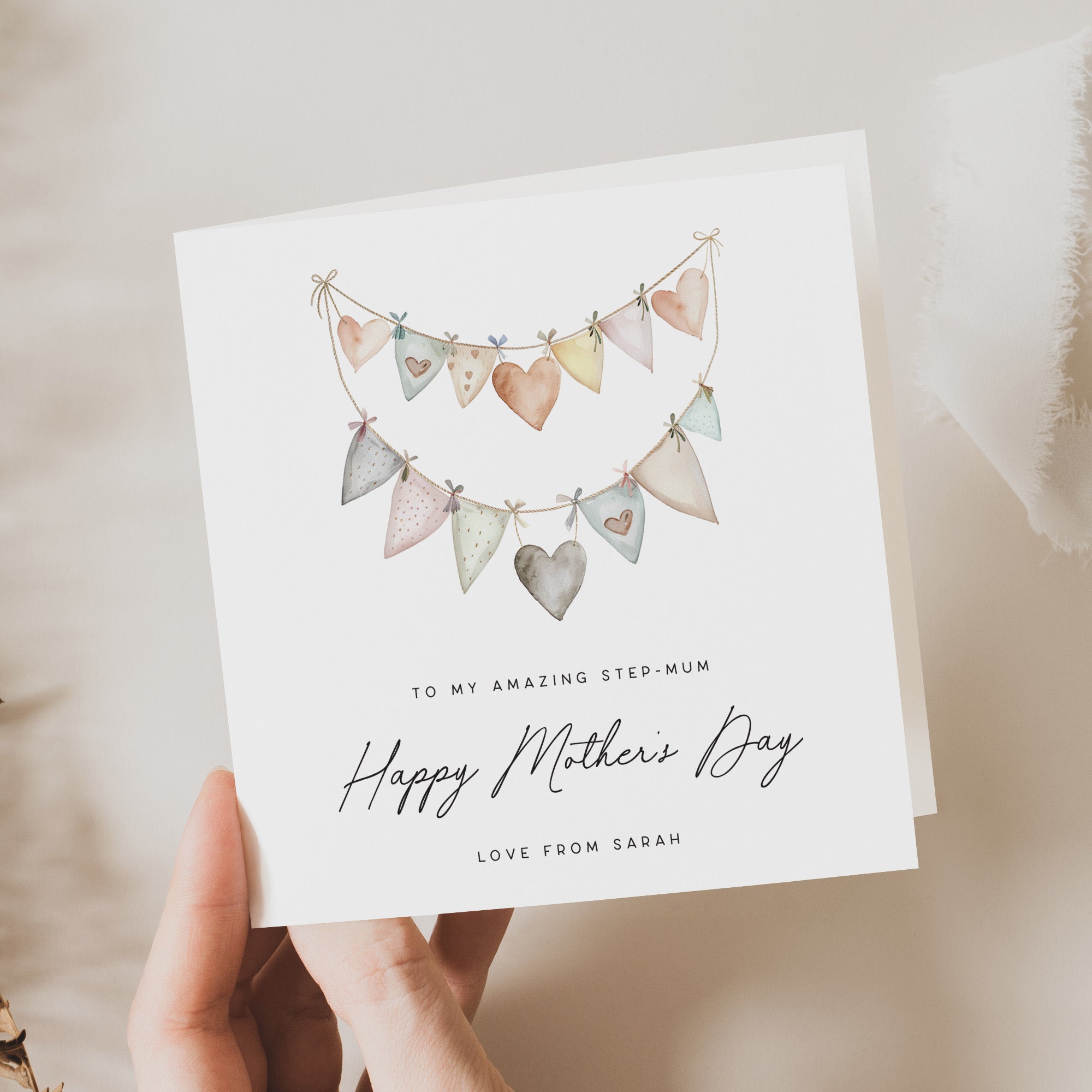 Greeting card with heart-shaped bunting design and personalized text, held by a hand.