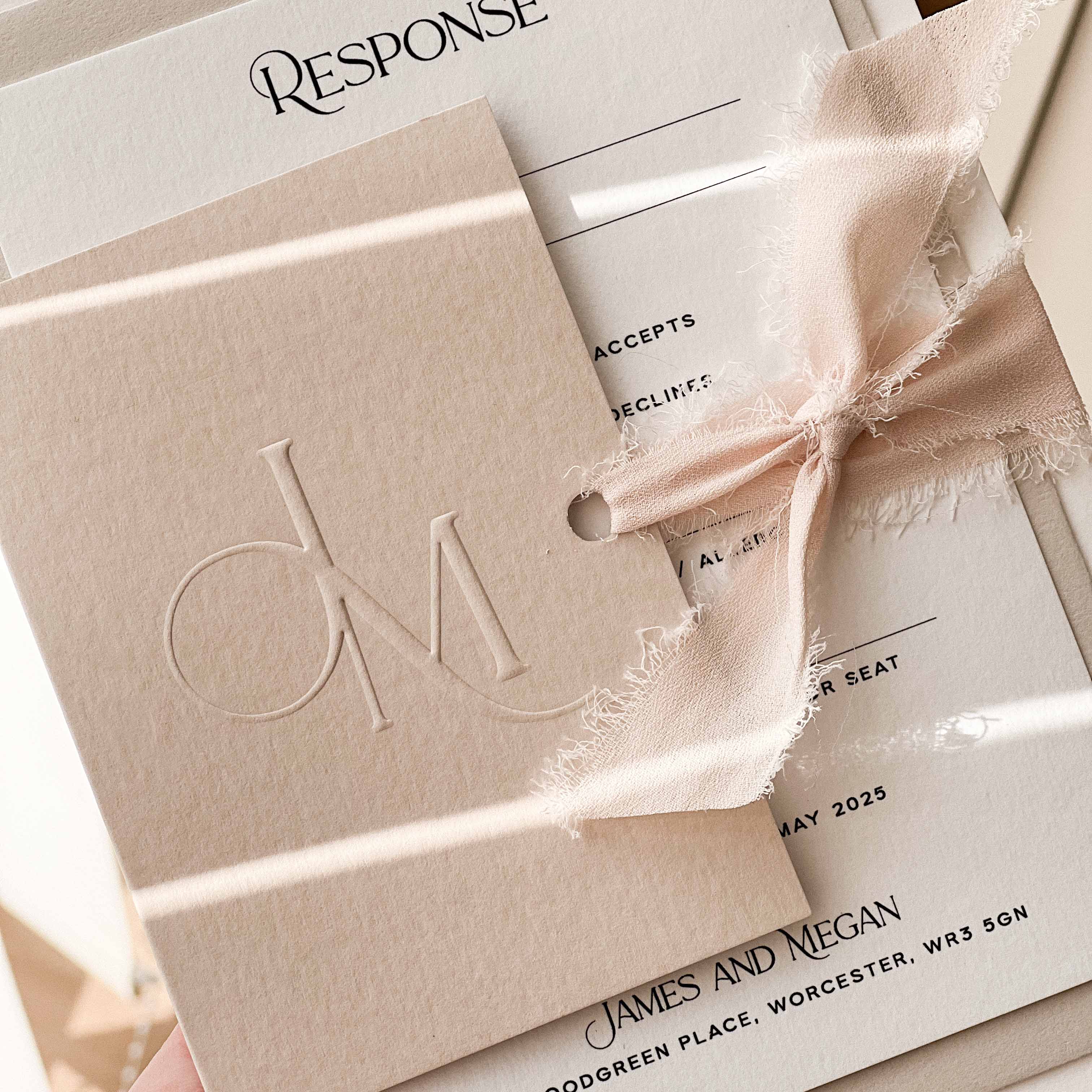 Wedding invitation with embossed monogram and bow detail