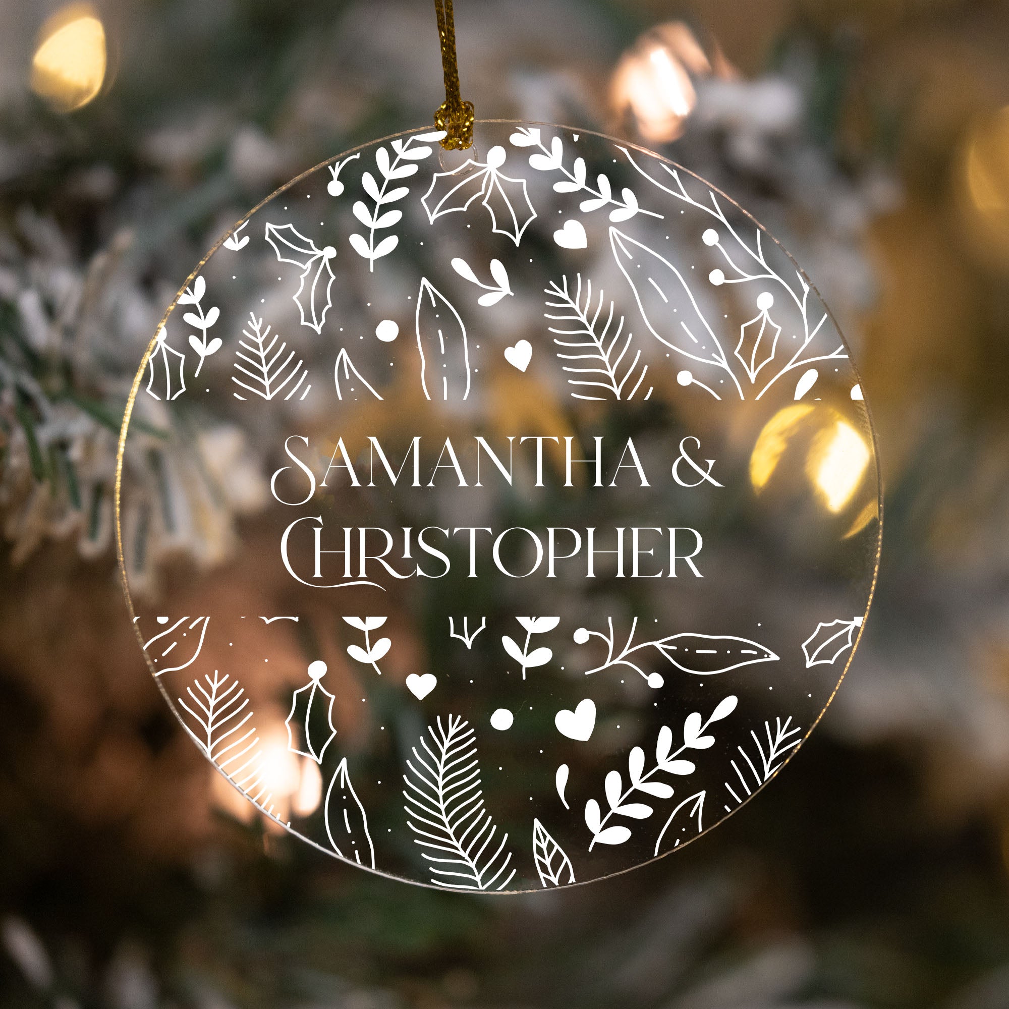 Decorative ornament with 'Samantha & Christopher' text against a blurred Christmas tree background.