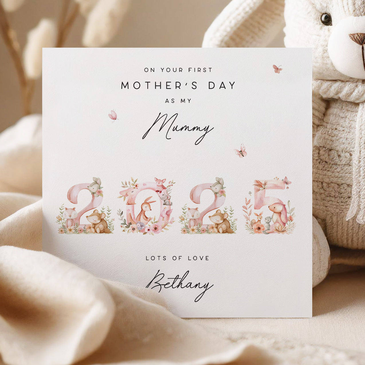 Greeting card for first Mother's Day with floral numbers and teddy bear illustrations, placed on a soft surface.